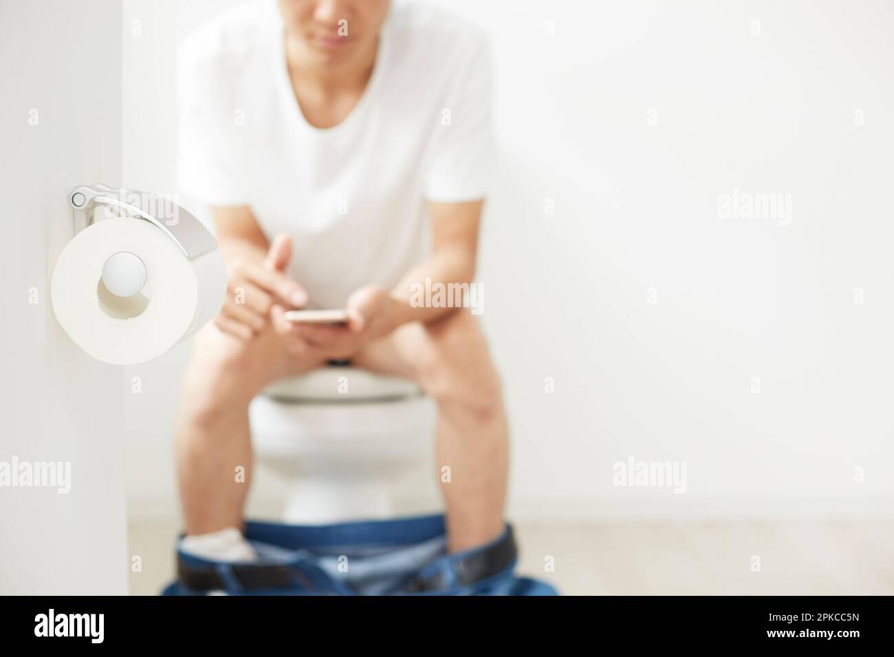 Toilettenpapier und ein Mann, der ein Handy bedient Stockfoto