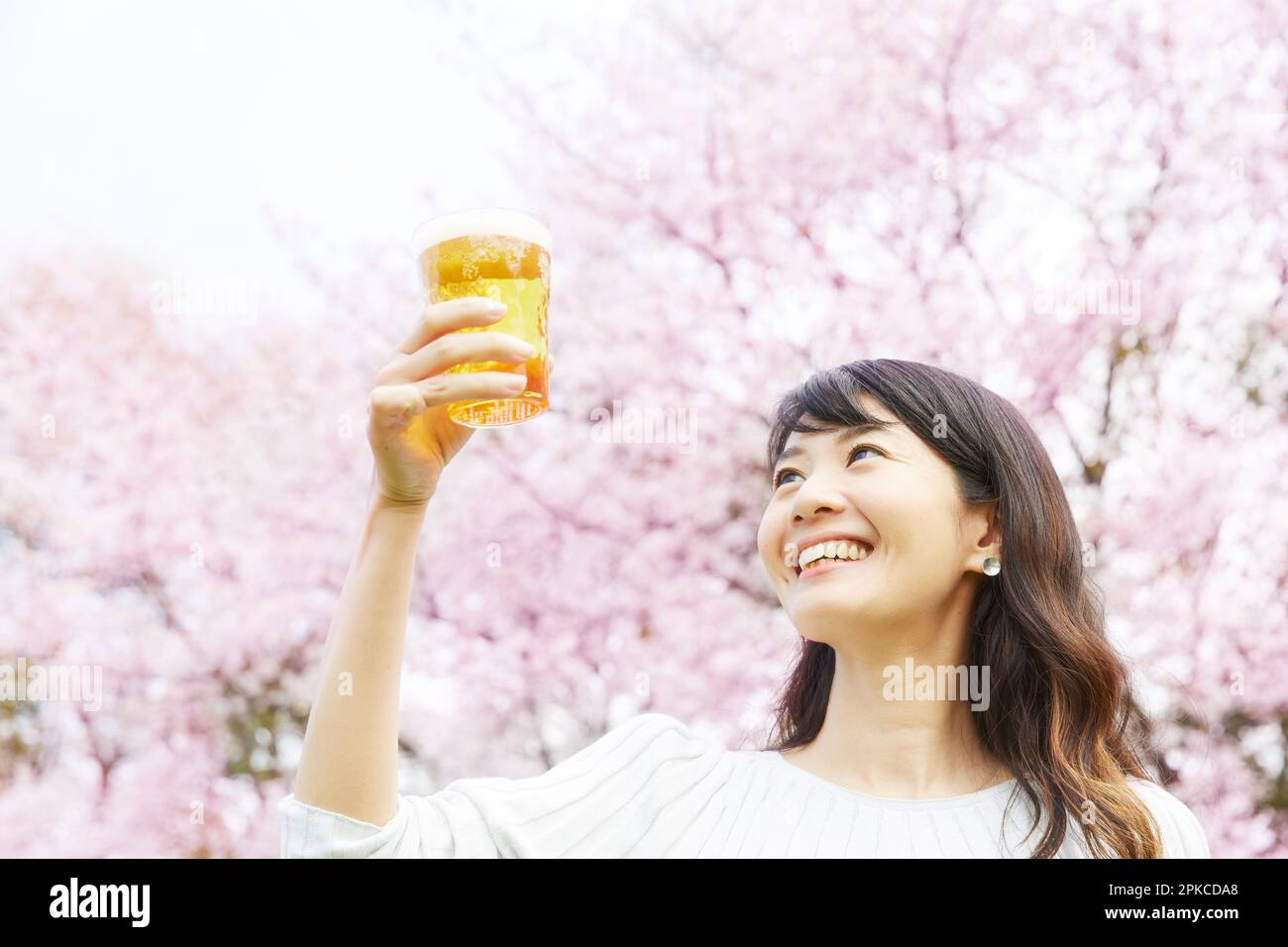 Eine Frau, die Bier unter dem Kirschbaum trinkt Stockfoto