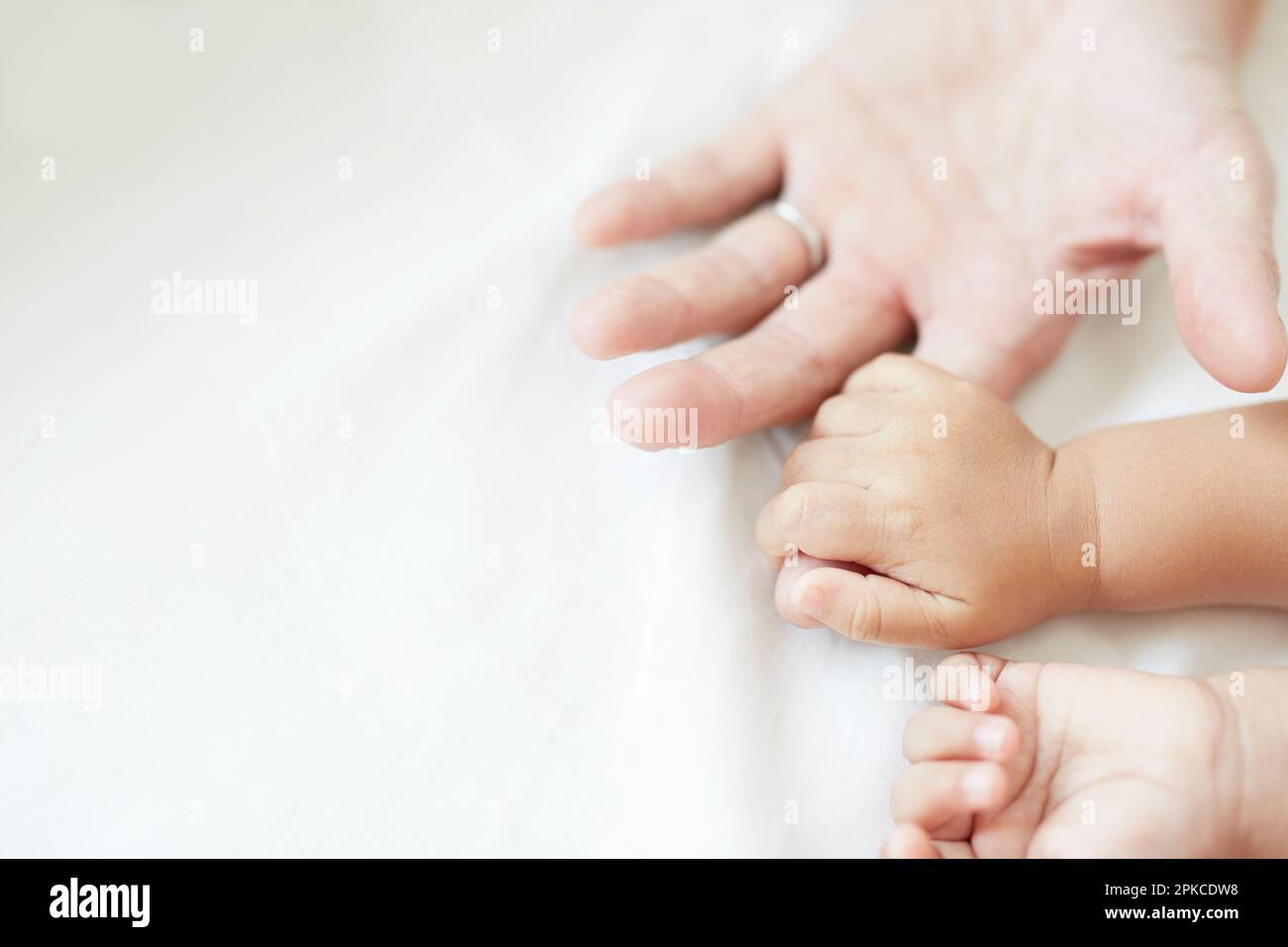 Babyhände, die Vaters Hände umklammern Stockfoto