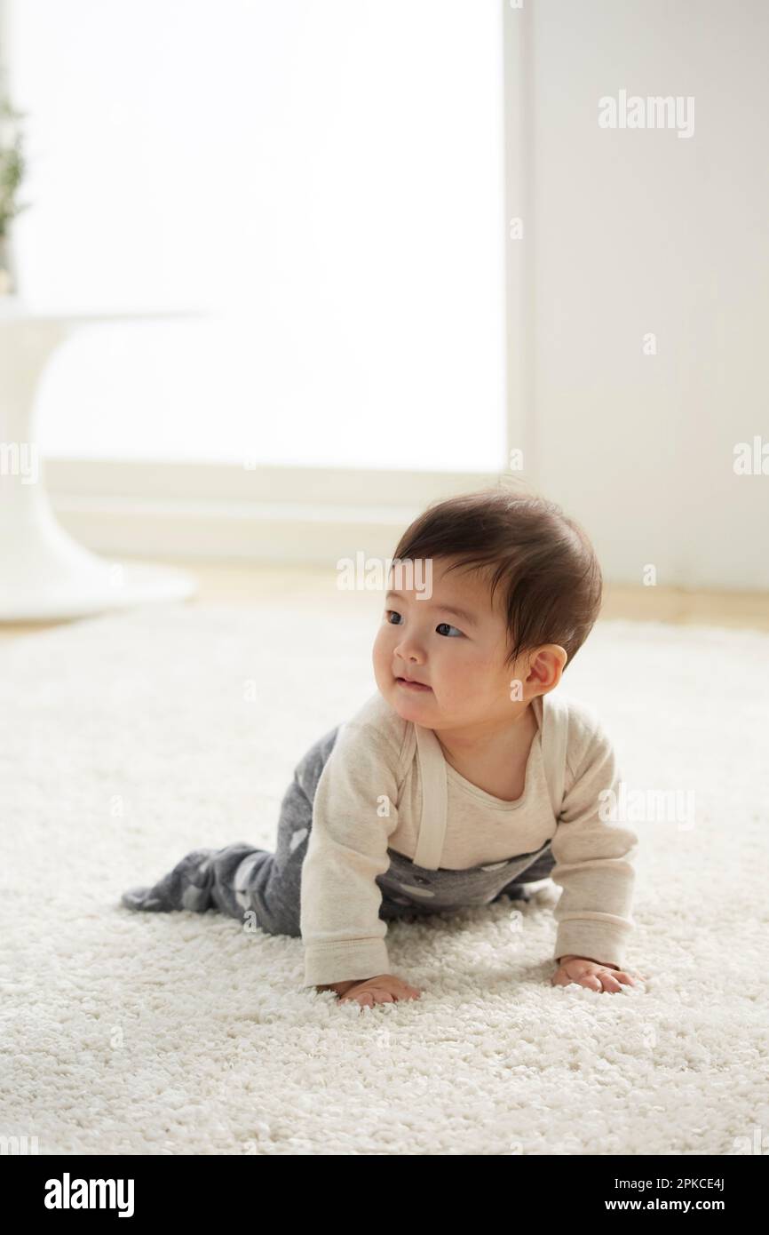 Baby krabbelt auf weißem Teppich Stockfoto
