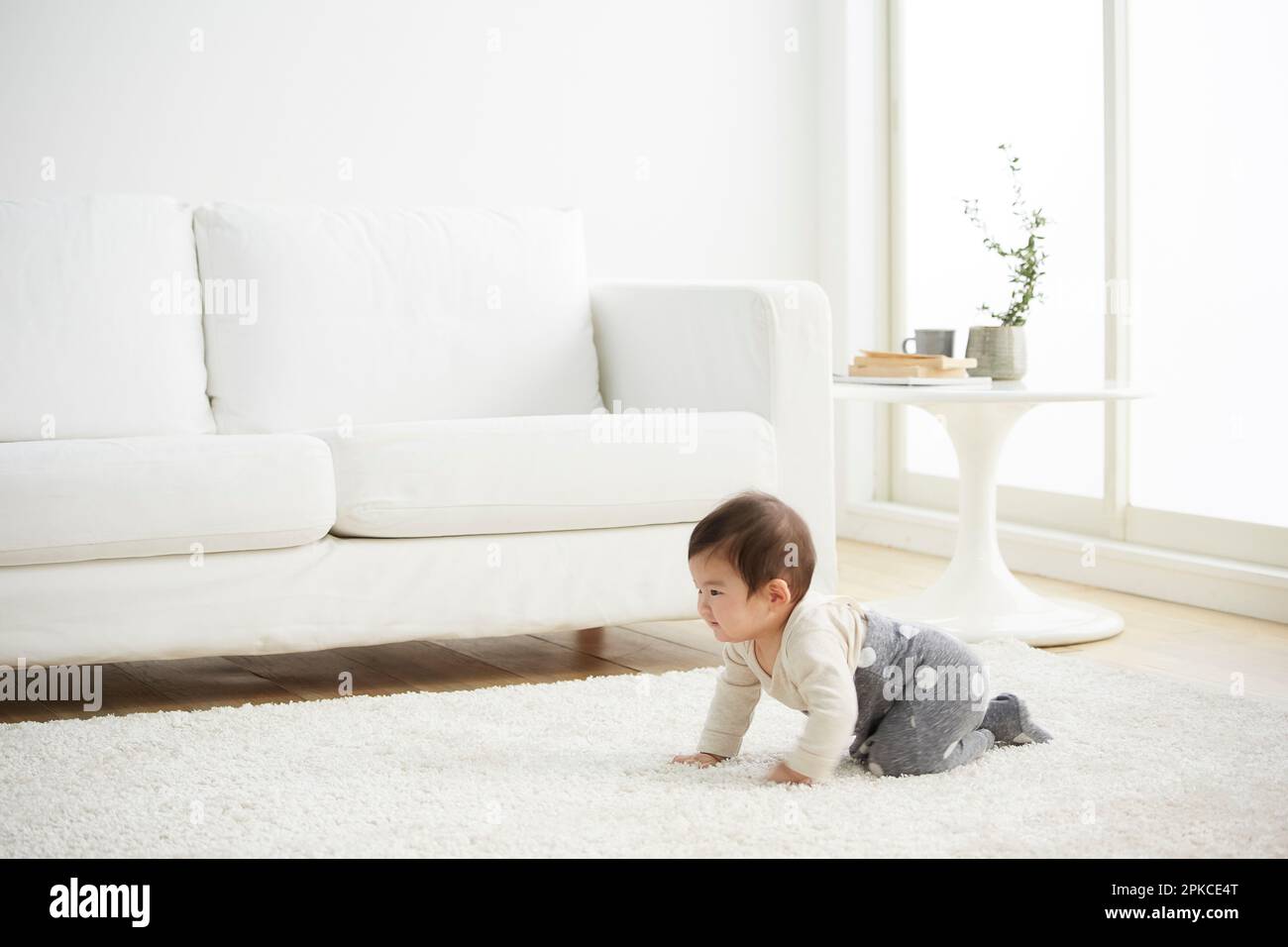 Baby krabbelt in einem weißen Raum Stockfoto