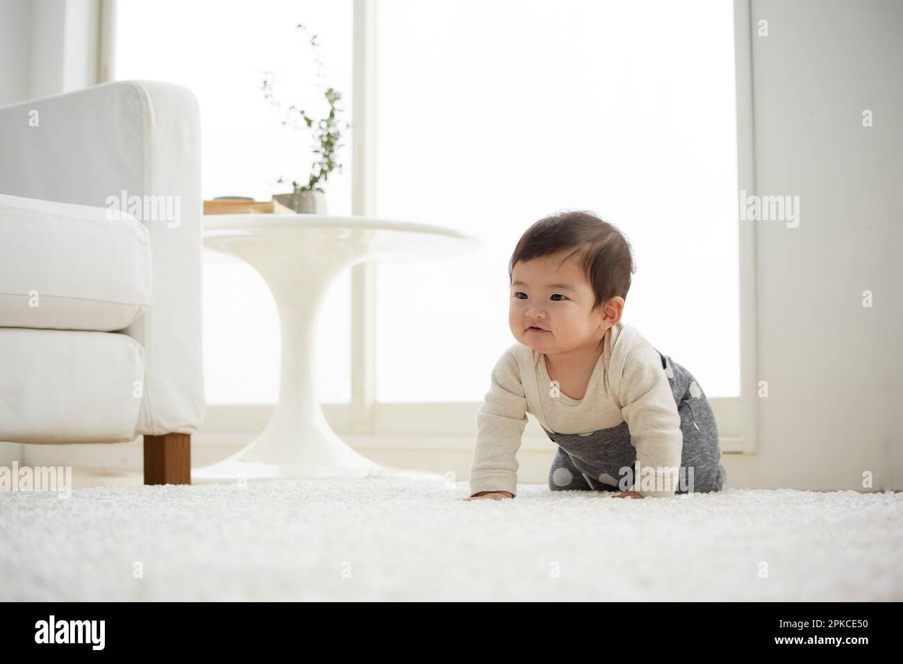 Baby krabbelt in einem weißen Raum Stockfoto