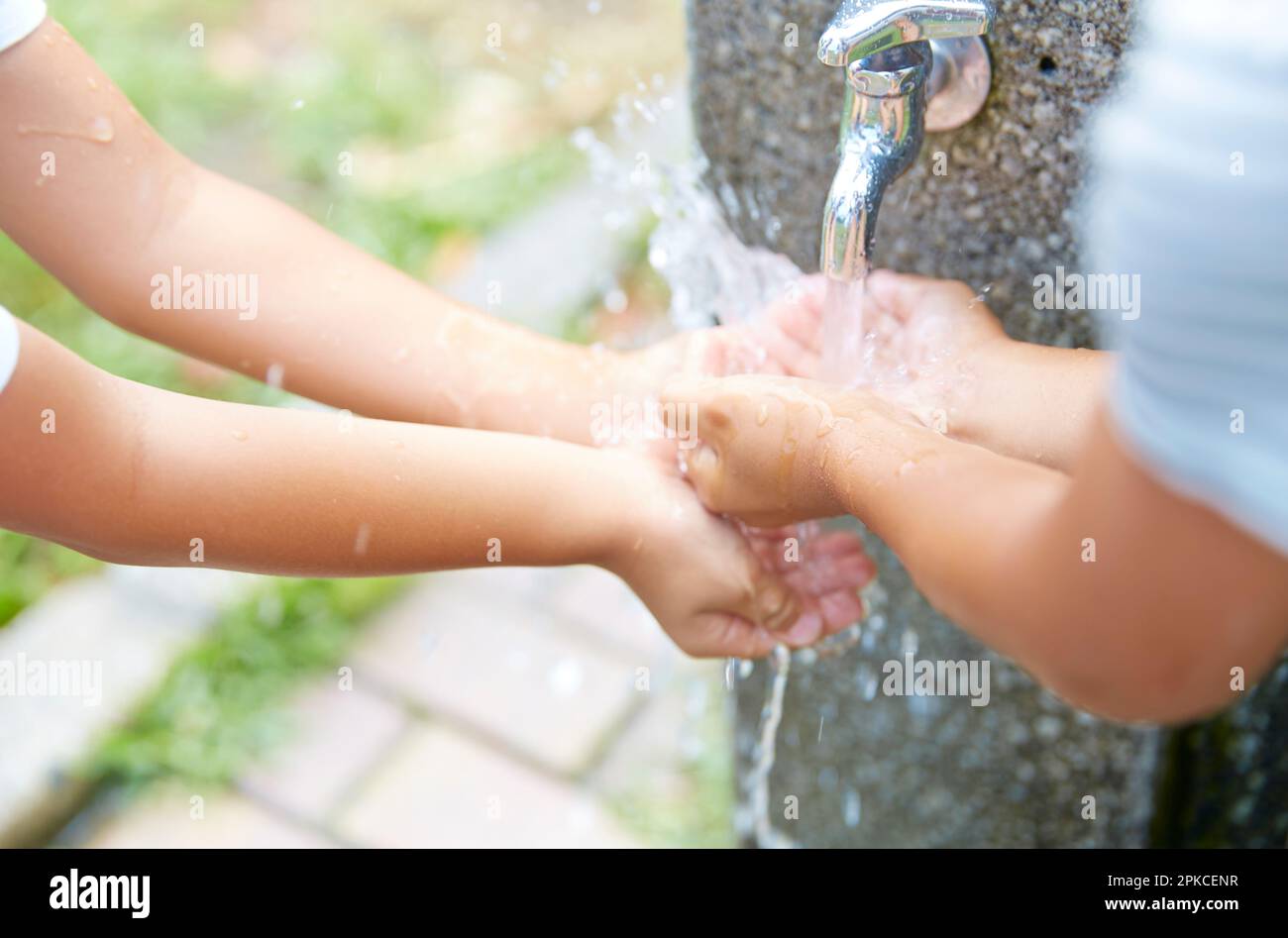 Kinderhände, die mit Wasser aus dem Wasserhahn spielen Stockfoto