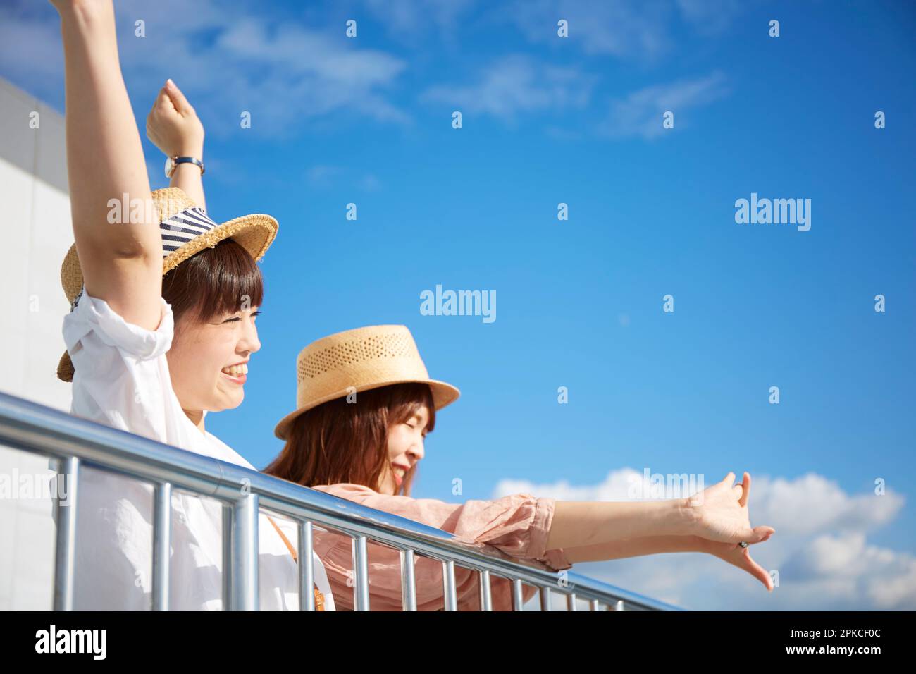 Zwei Frauen, die ihre Hände gegen den blauen Himmel strecken Stockfoto