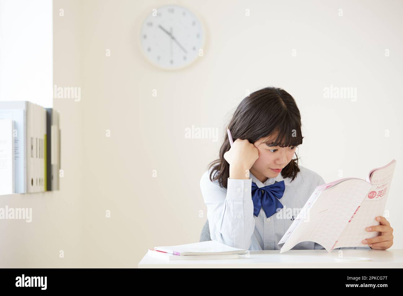 Ein Highschool-Mädchen, das denkt, mit einem offenen Nachschlagewerk Stockfoto