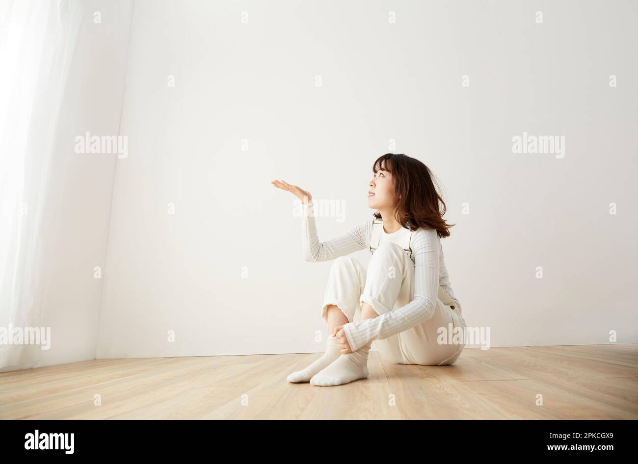 Eine Frau, die vor der weißen Wand sitzt Stockfoto