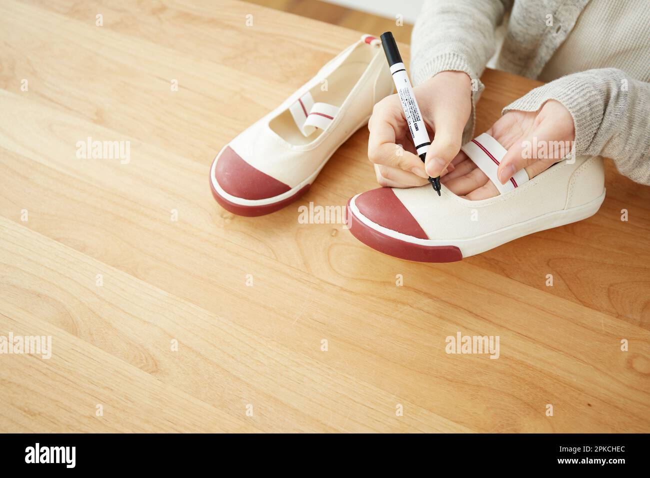 Eine Frau, die den Namen eines Kindes auf einen Schuh schreibt Stockfoto