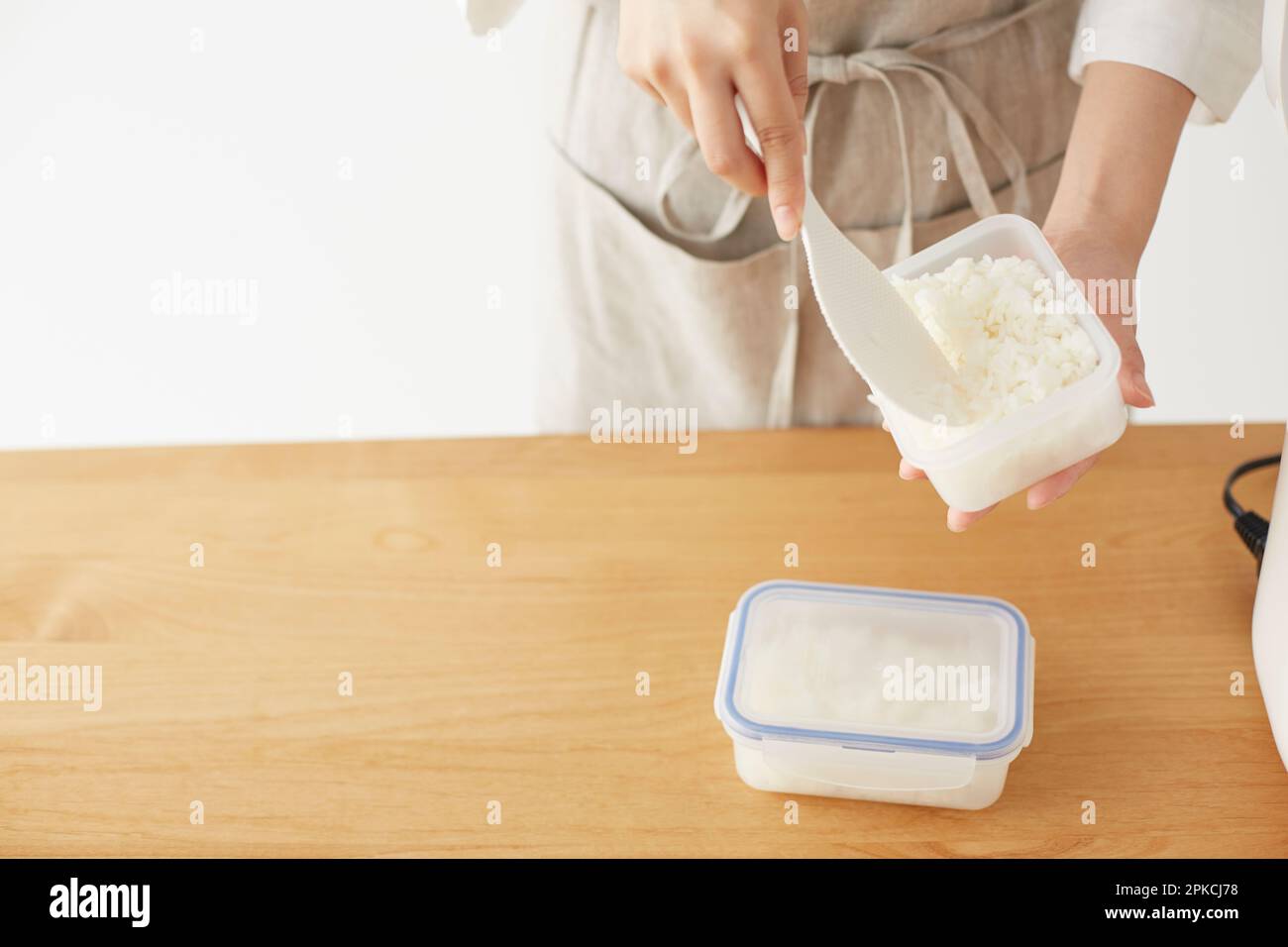 Eine Frau, die weißen Reis in Tupperware packt Stockfoto