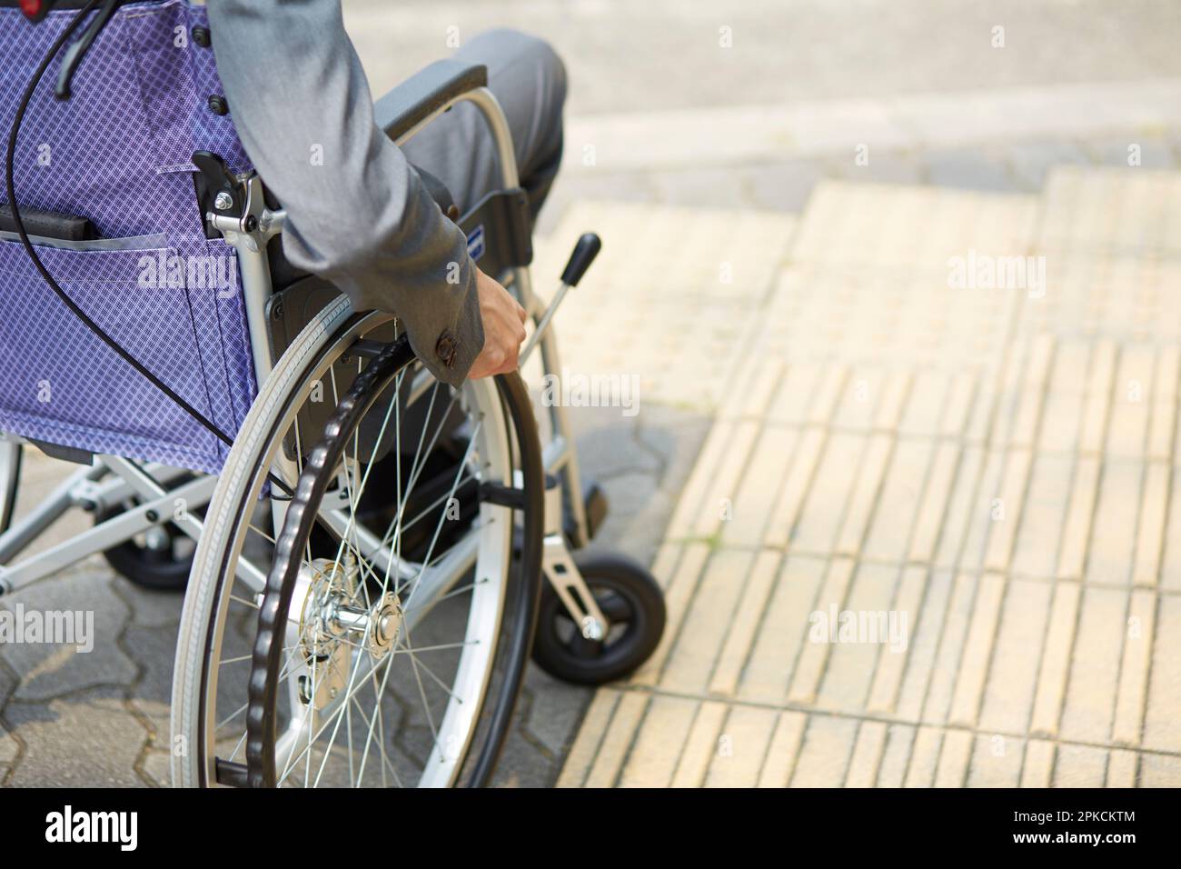 Mann im Anzug im Rollstuhl und auf der Straße Stockfoto