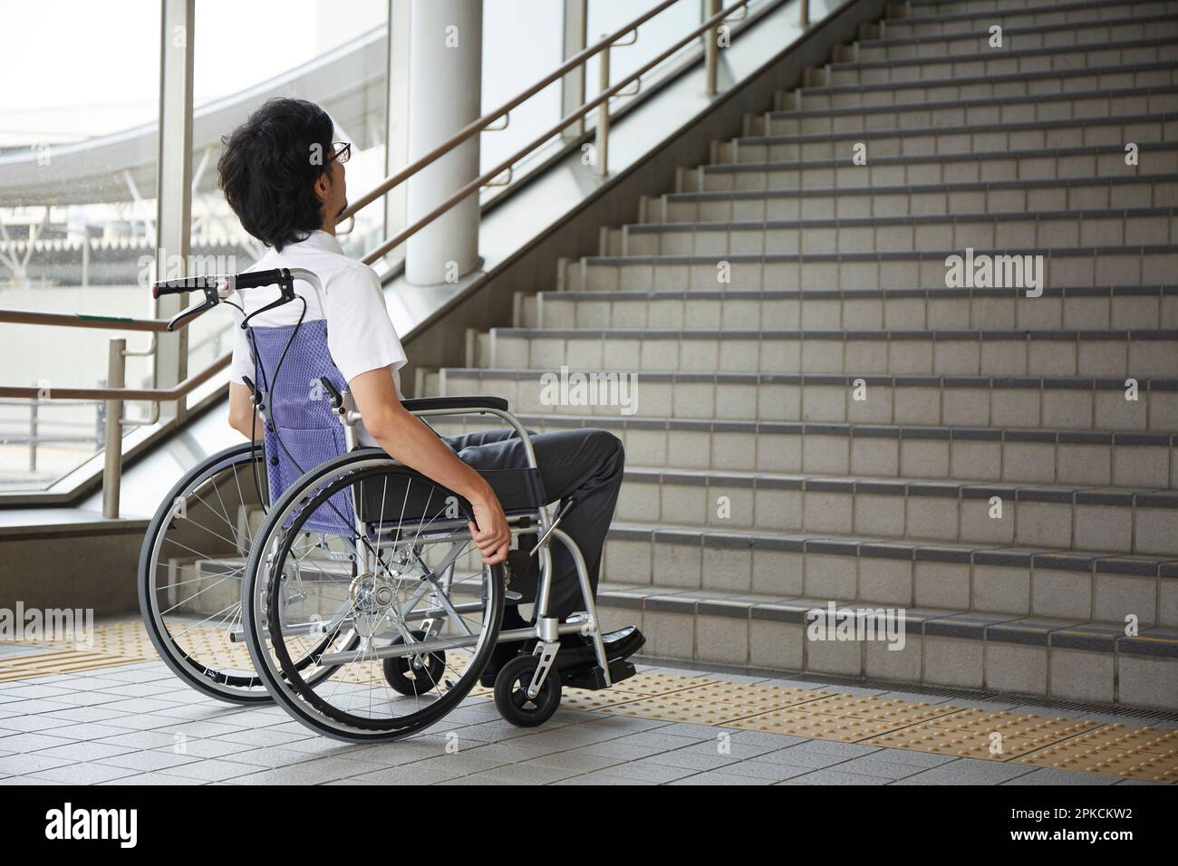 Ein Mann im Rollstuhl hält vor der Treppe Stockfoto