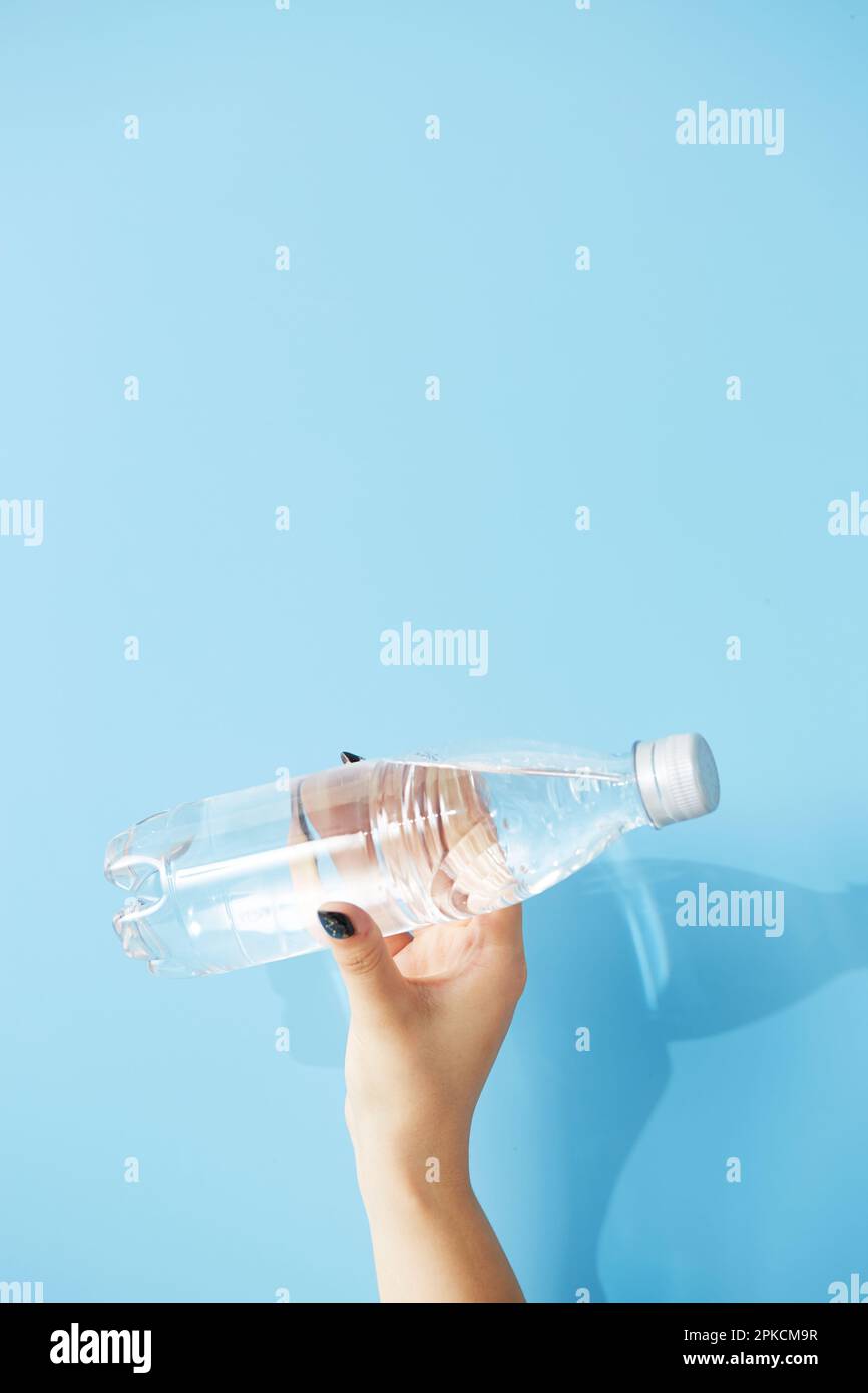 Frauenhand mit Plastikflasche auf hellblauem Hintergrund Stockfoto