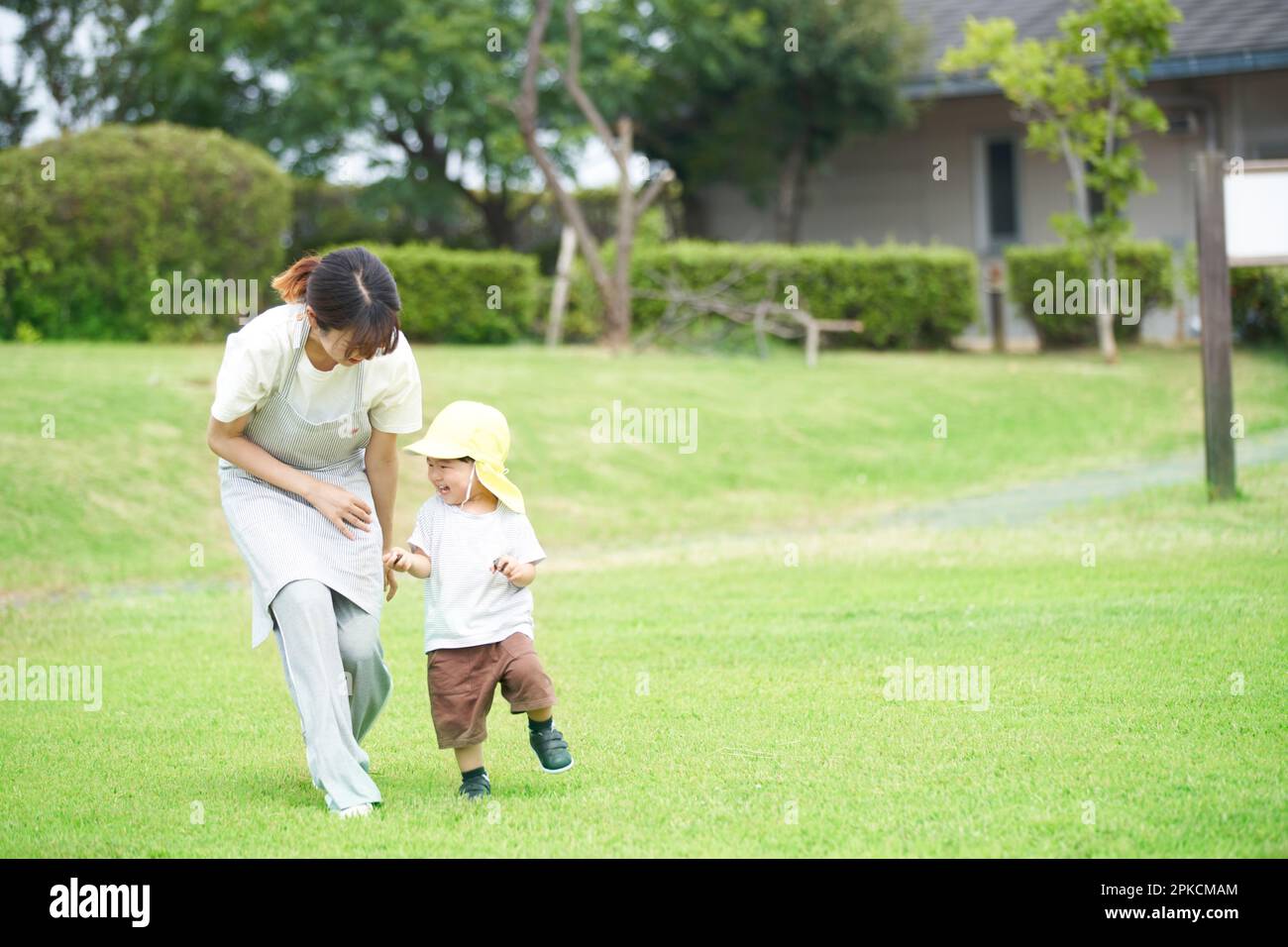 Kinder und Frauen, die im Kindergarten auf dem Rasen spielen Stockfoto