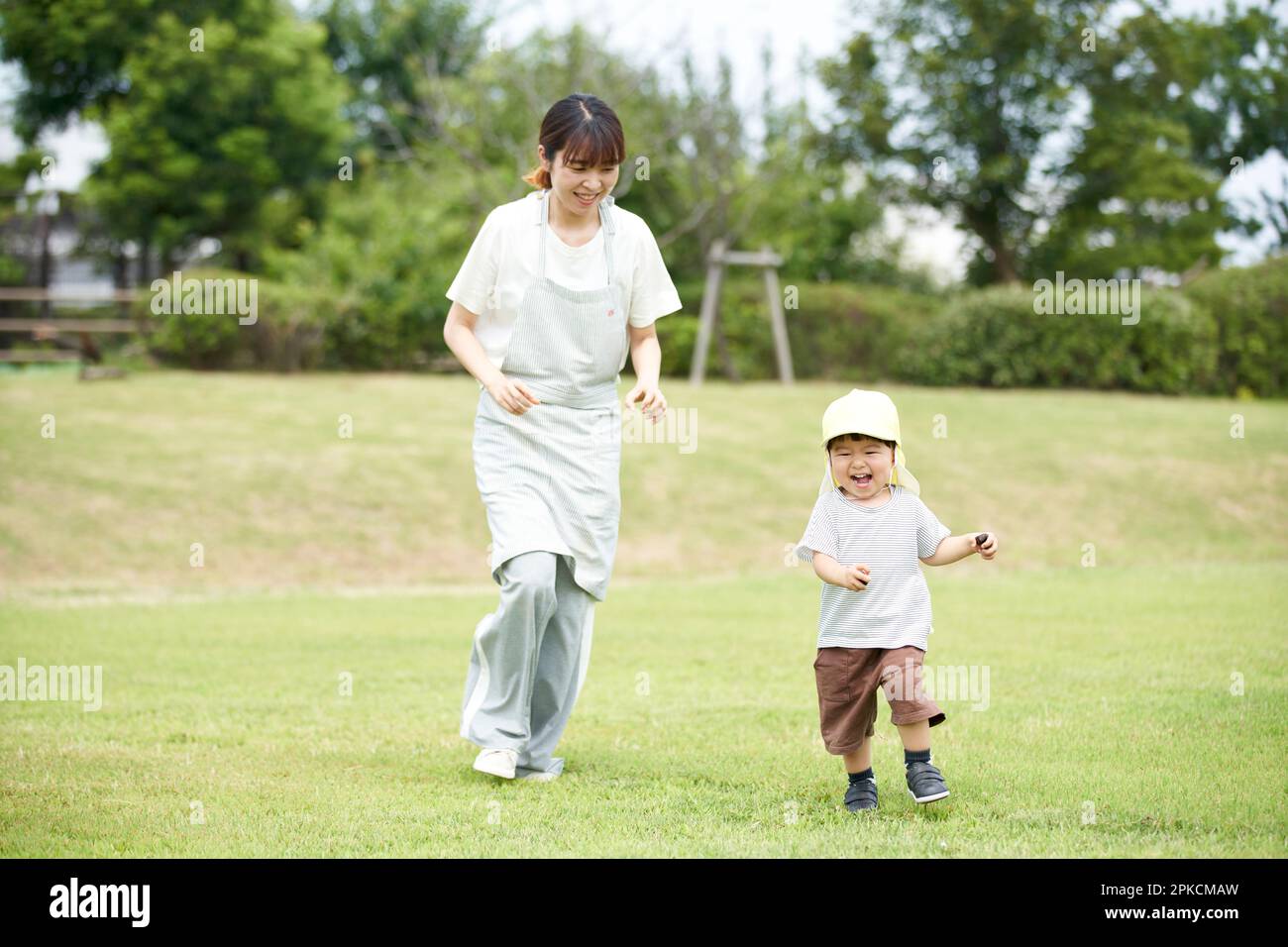 Kind und weibliche Kinderbetreuerin, die auf dem Rasen spielt Stockfoto