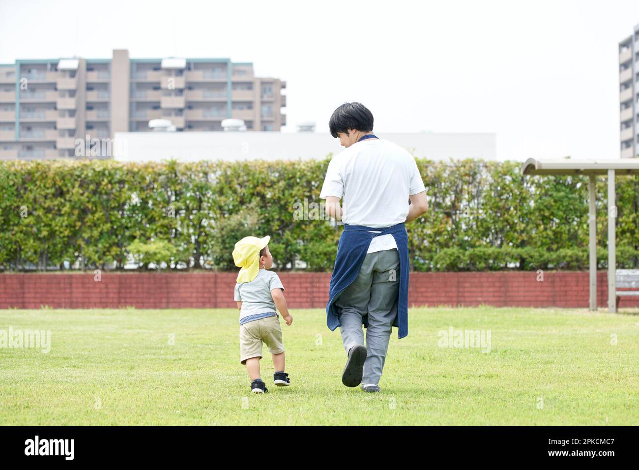 Männlicher Kinderbetreuer mit Kind, das auf dem Rasen spielt Stockfoto