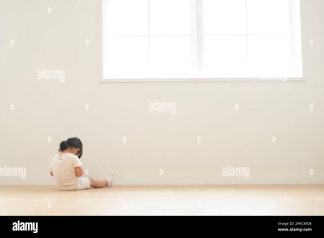 Rückansicht eines Kindes, das in der Ecke des Zimmers sitzt Stockfoto
