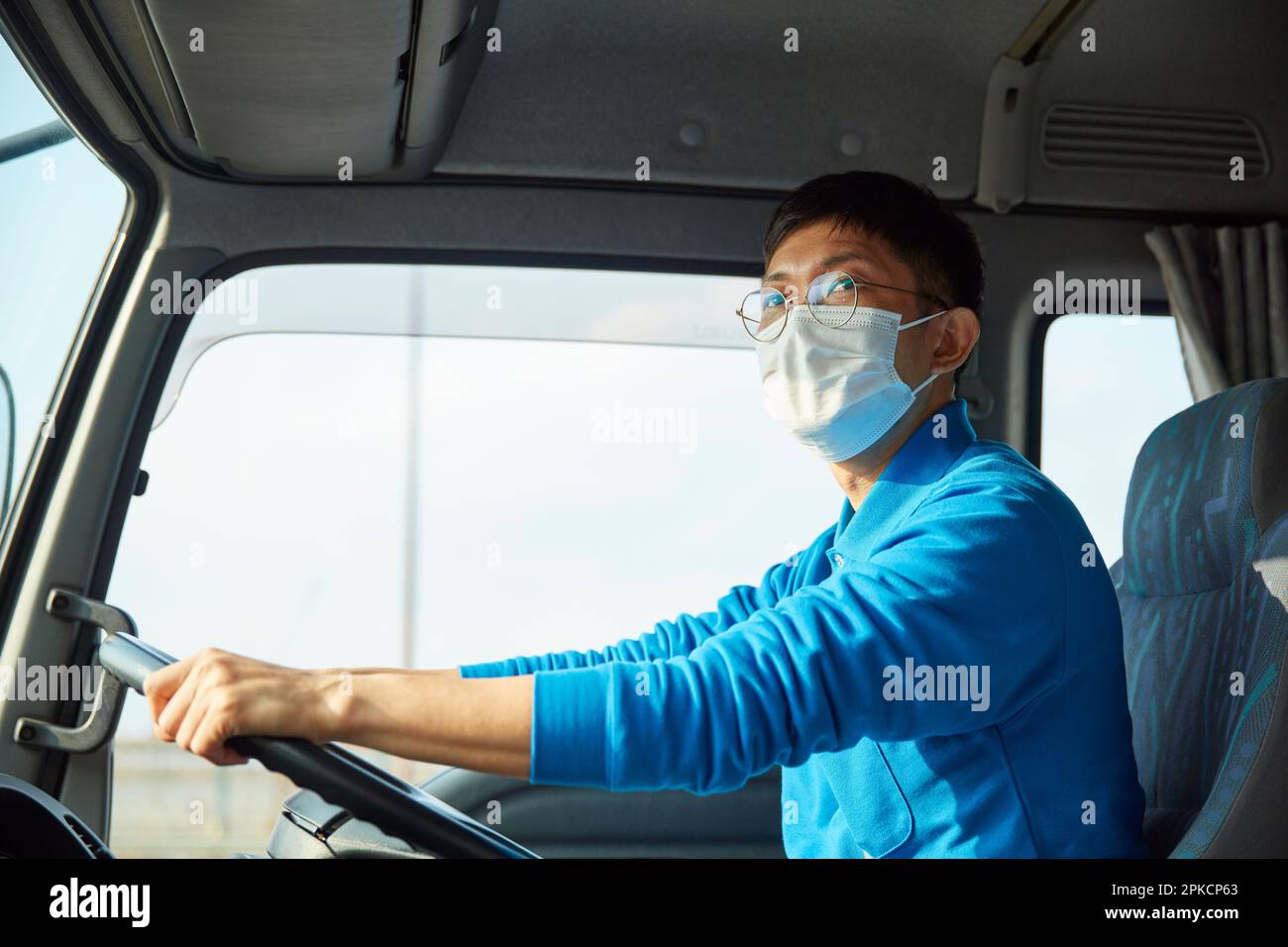 Mann in Arbeitskleidung und Maske, der einen Truck fährt Stockfoto