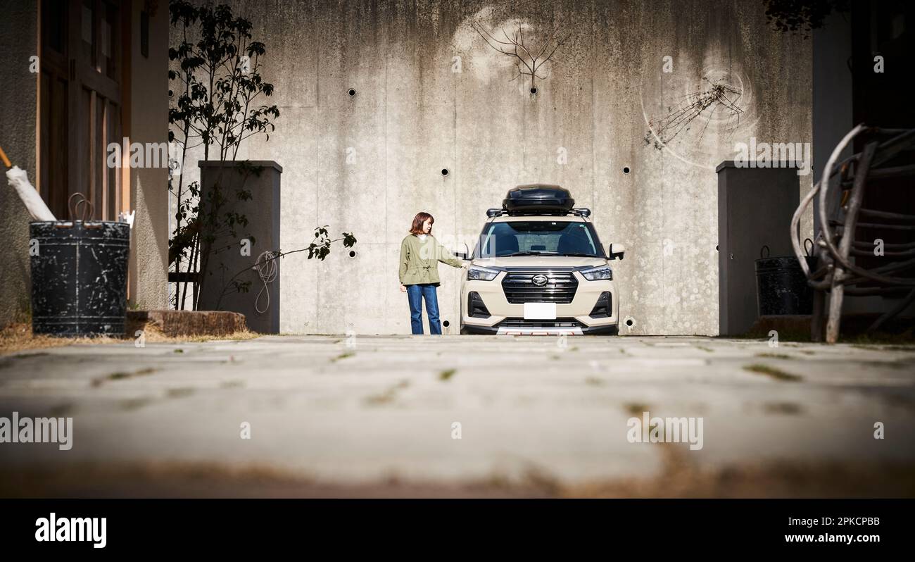 Eine Frau, die ihre Hand auf ein geparktes Auto legt Stockfoto