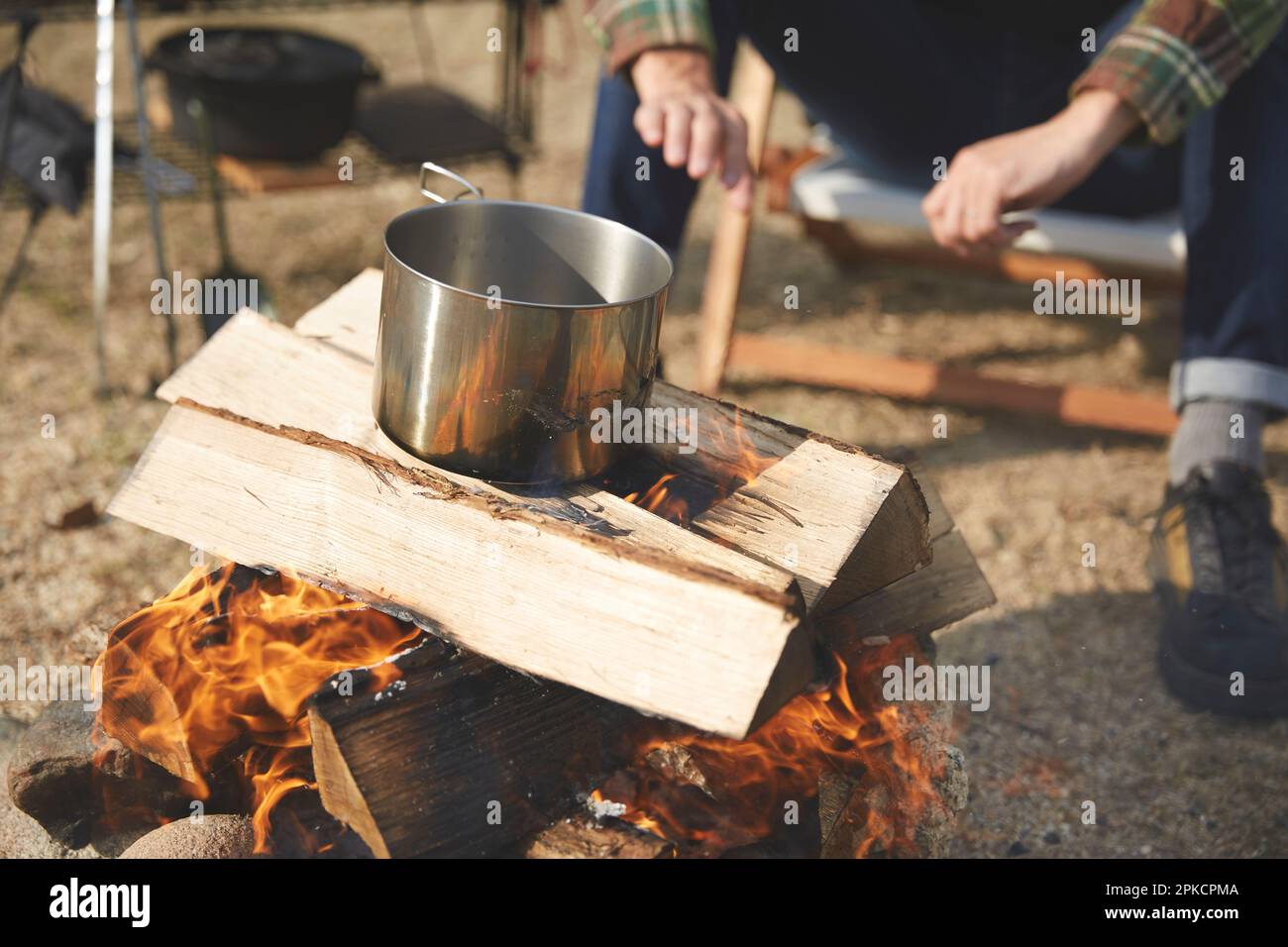 Mann, der Wasser über einem offenen Feuer erhitzt Stockfoto