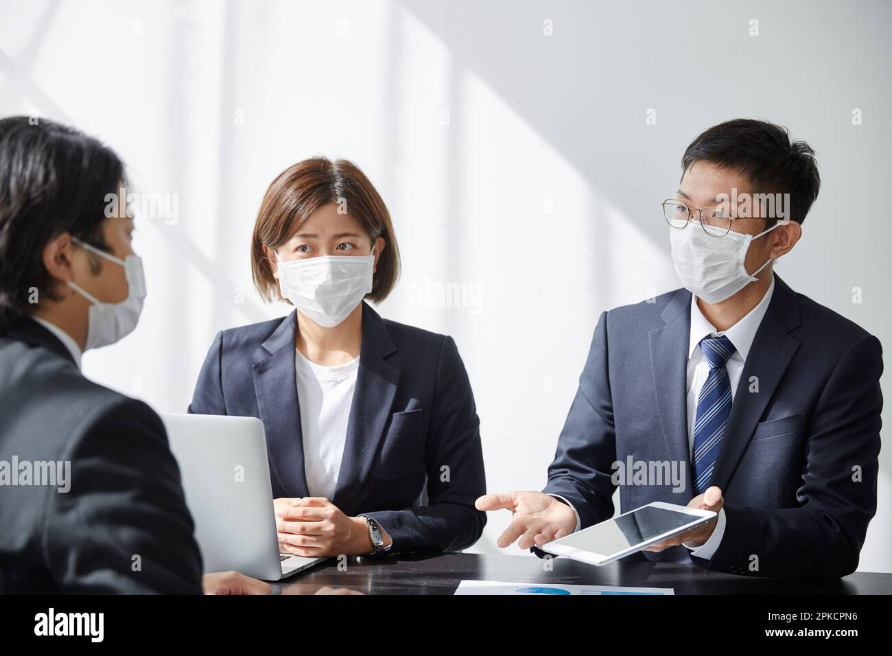 Büroangestellter diskutiert Geschäft im Büro mit Maske Stockfoto