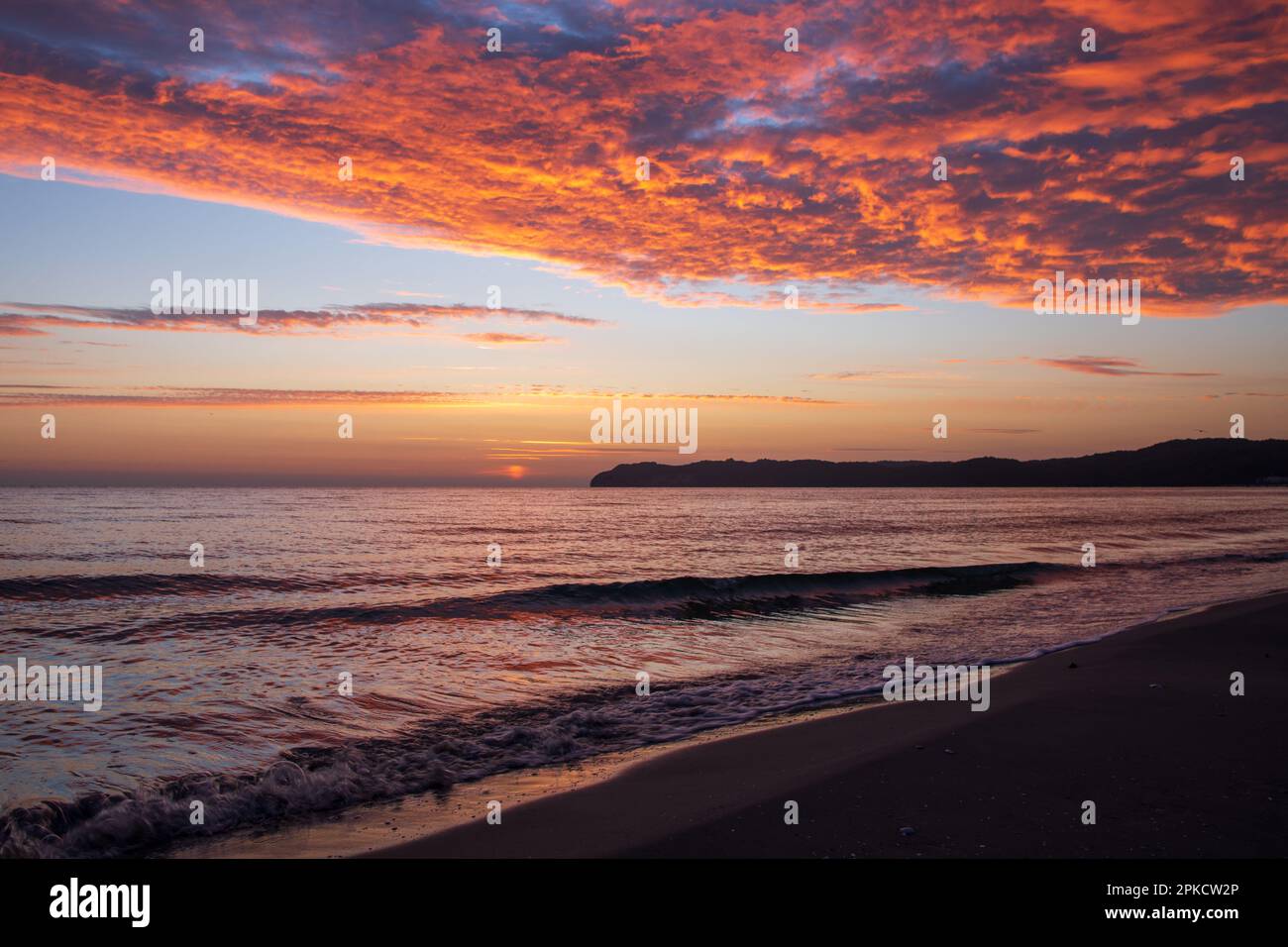 Ein spektakulärer, feuriger Sonnenaufgang färbt die Wolken orange und rot über der Ostsee, von einem Sandstrand auf der Insel Rügen aus gesehen. Stockfoto