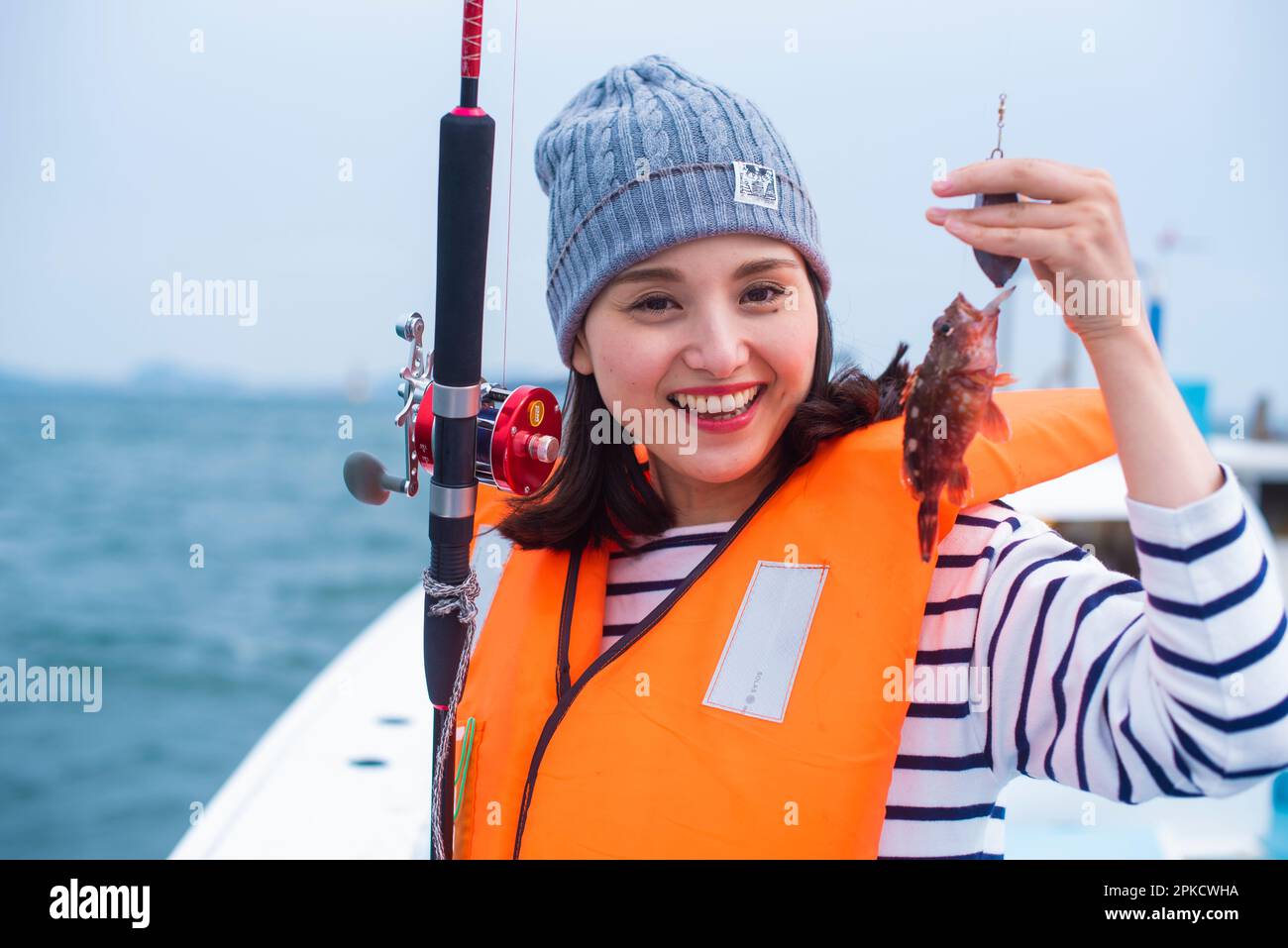 Eine Frau in ihren 20s mit einem Skorpionfisch, den sie gefangen hat Stockfoto