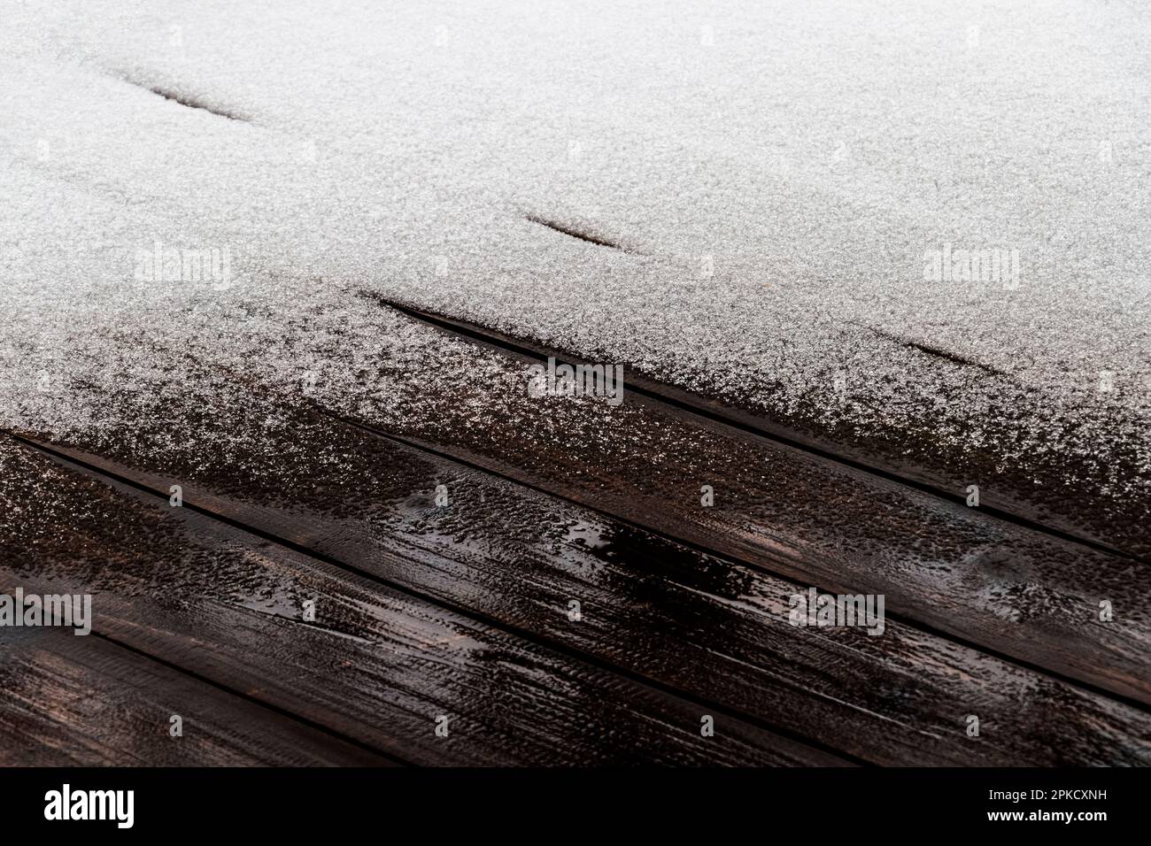 Schnee schmilzt auf dem Holzboden der offenen Veranda eines Privathauses. Stockfoto