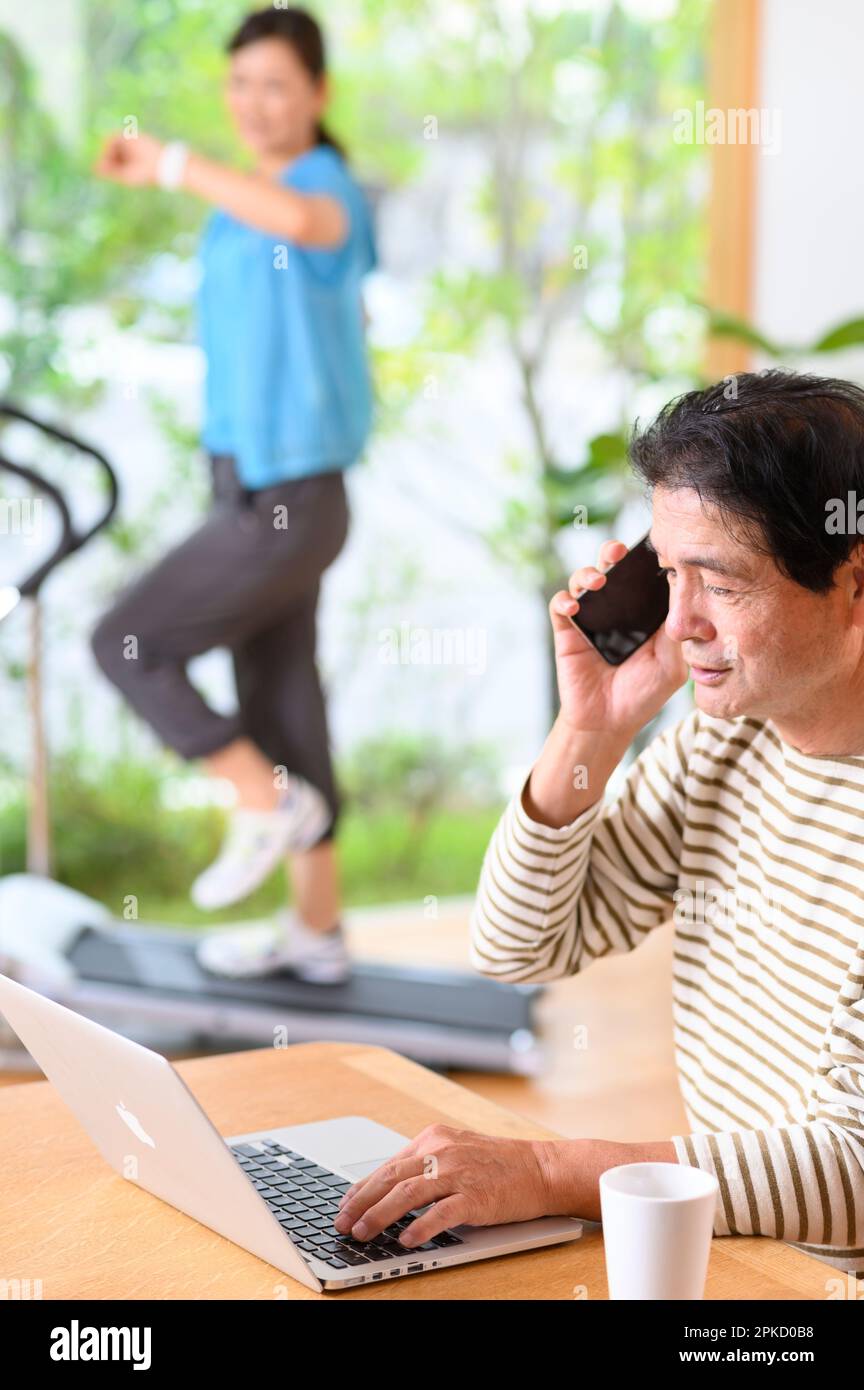 Telearbeit von Mann und Frau mittleren Alters mit einer Laufmaschine Stockfoto