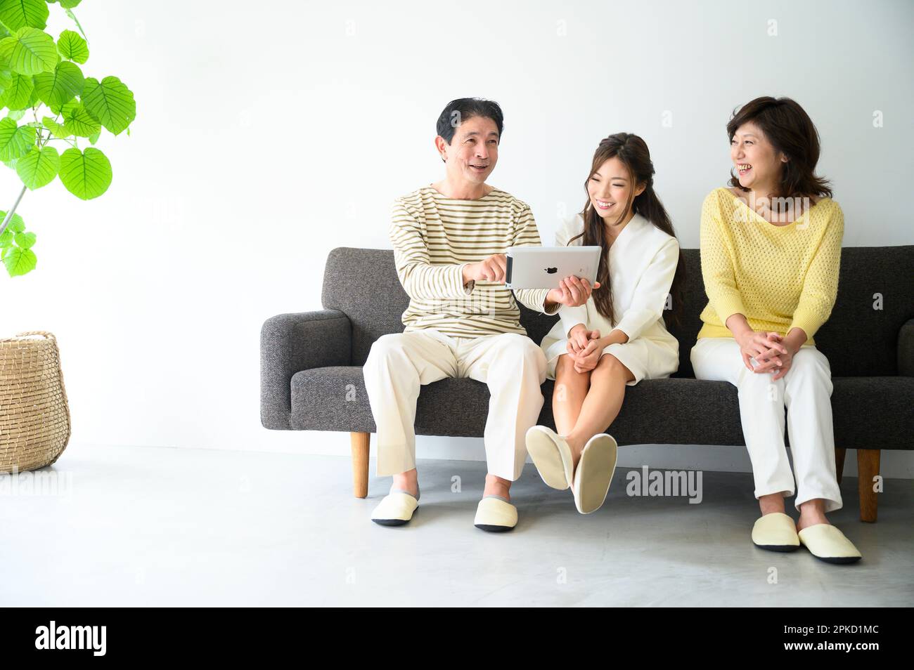 Familie, die auf dem Sofa im Wohnzimmer sitzt und den PC ansieht Stockfoto