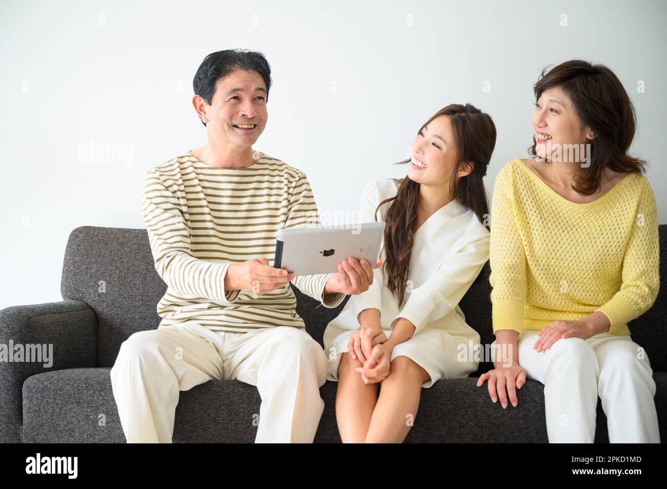 Familie sitzt auf dem Sofa im Wohnzimmer und sieht sich den PC an Stockfoto