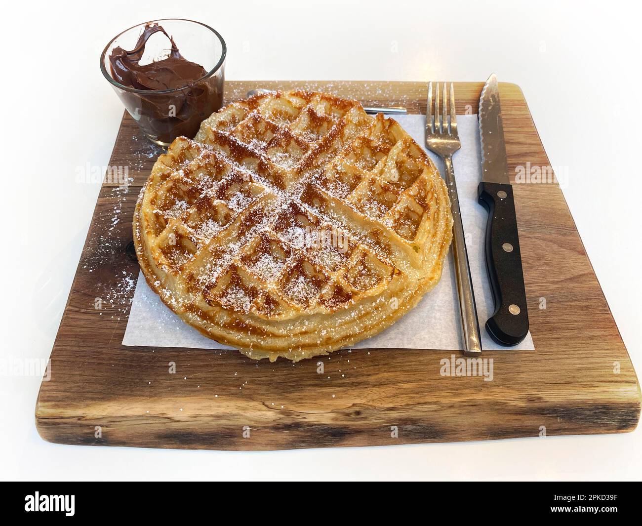 Belgische Waffeln mit Puderzucker, Nutella-Schokoladencreme, Besteck, auf Holzbrett, Stuttgart, Baden-Württemberg, Deutschland Stockfoto