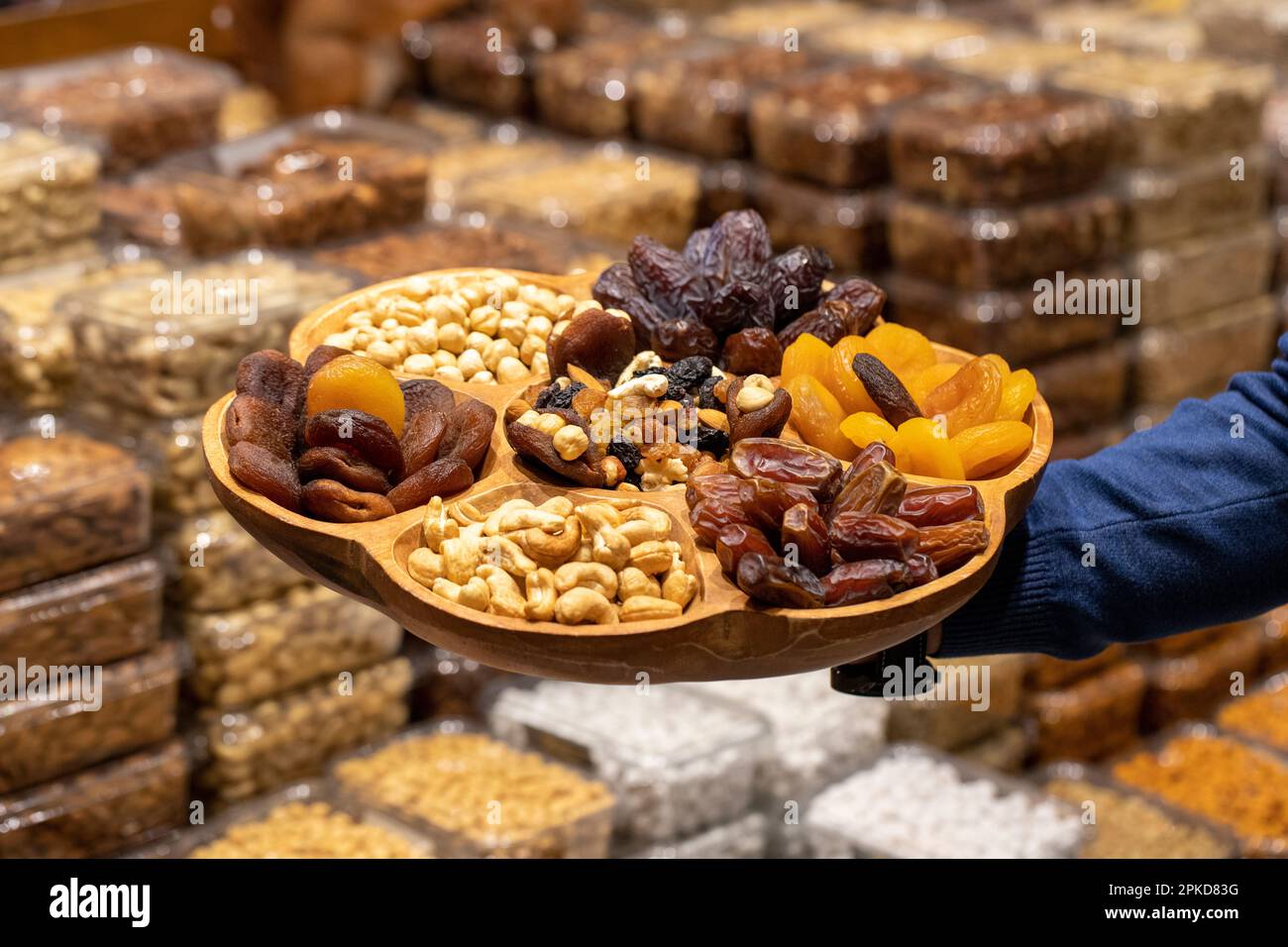 Gemischte Nussplatte. Holznussteller, zubereitet mit Haselnüssen, Cashews, Datteln, Aprikosen und Trauben. Stockfoto