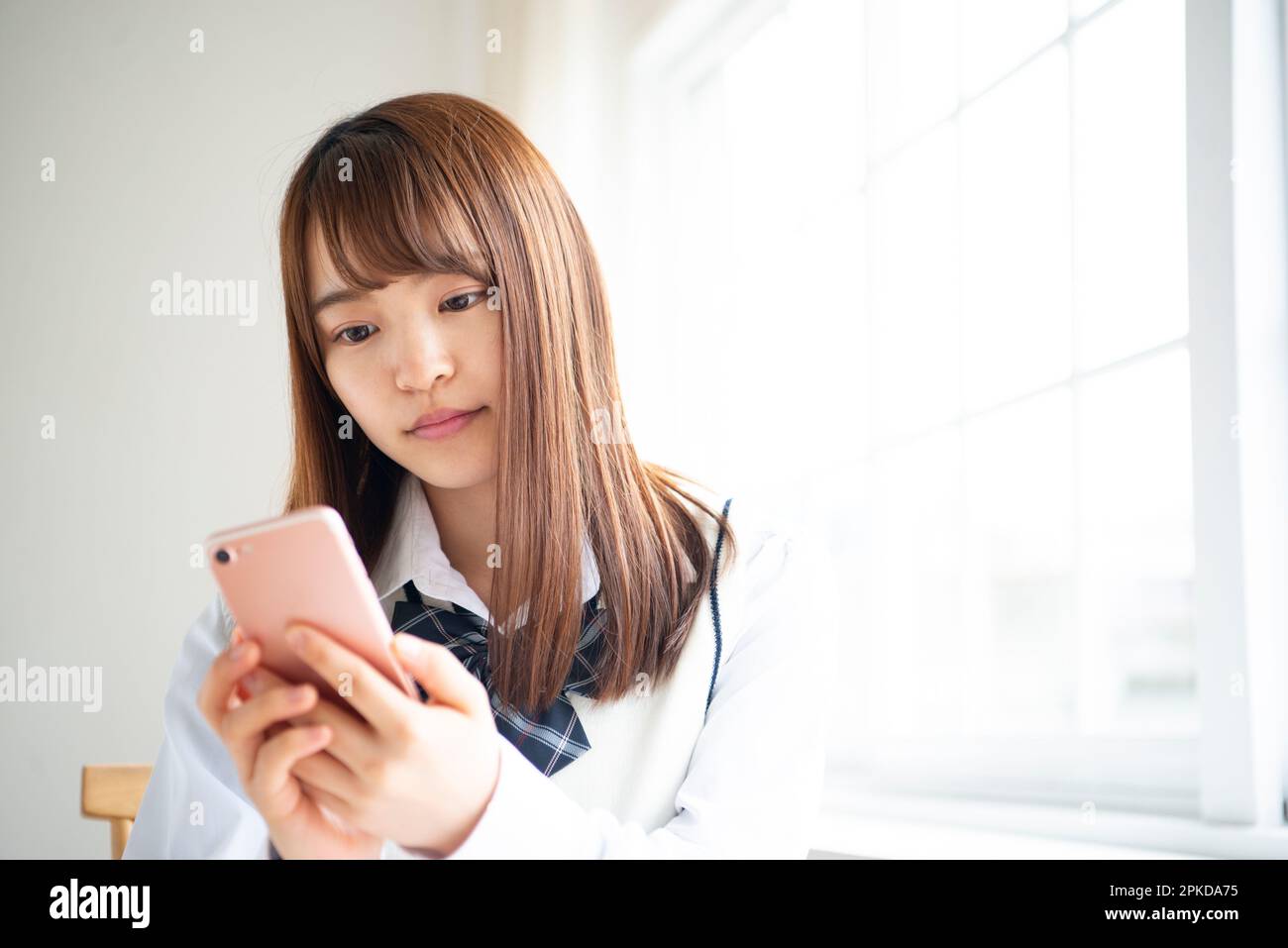 Ein Highschool-Mädchen, das auf ihr Handy schaut Stockfoto