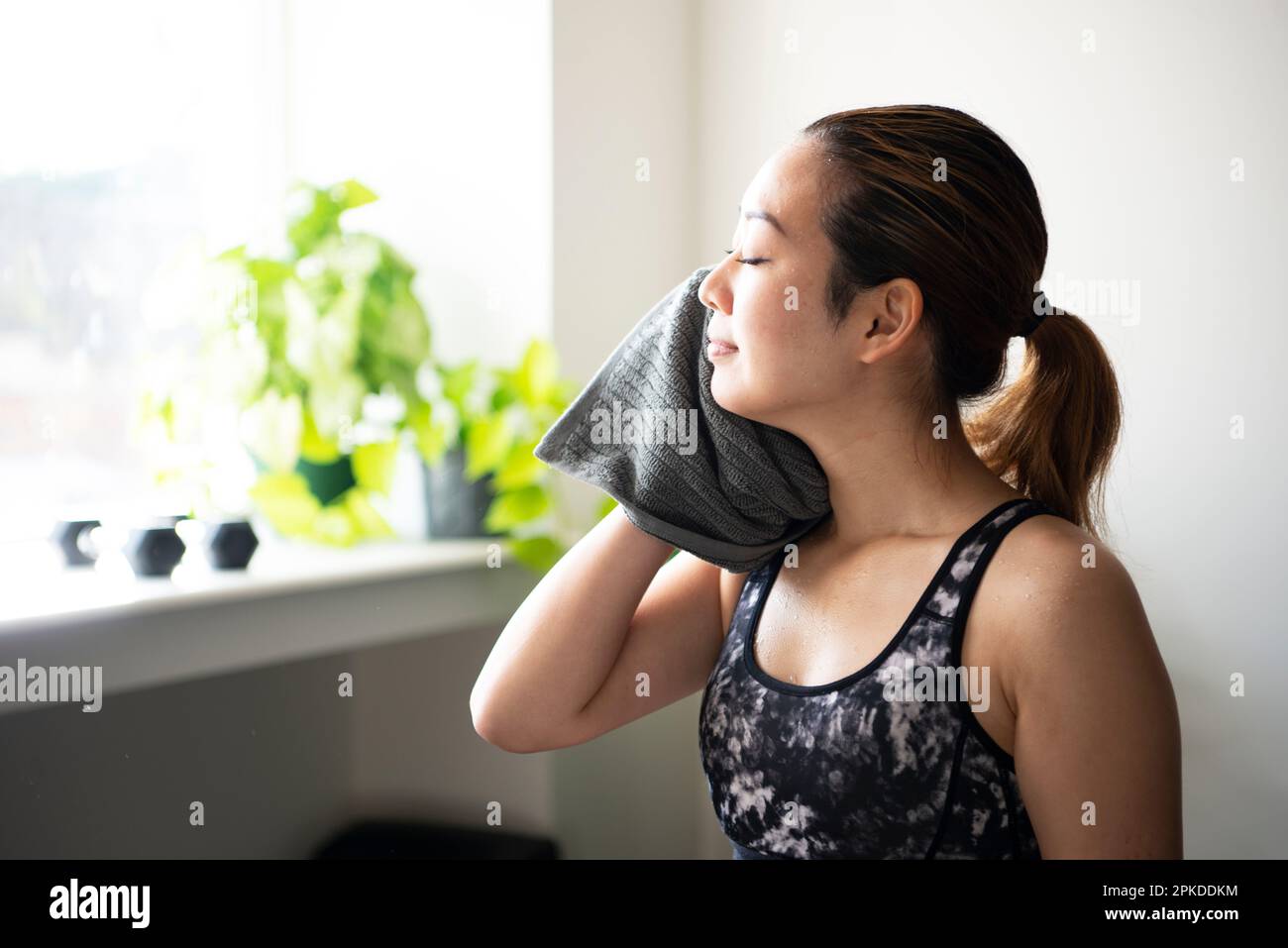 Eine Frau, die eine Pause macht, während sie im Fitnessstudio den Schweiß abwischte Stockfoto