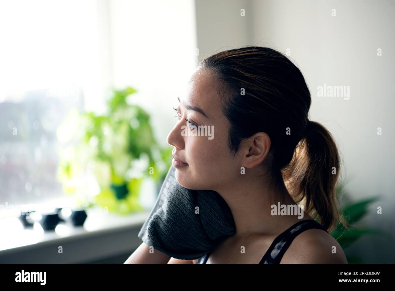 Eine Frau, die eine Pause macht, während sie im Fitnessstudio Schweiß abwischt Stockfoto