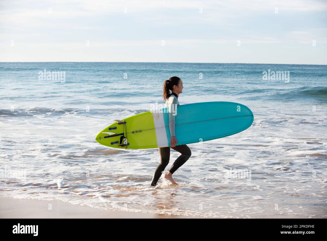 Frau in Neoprenanzug, die mit Surfbrett läuft Stockfoto
