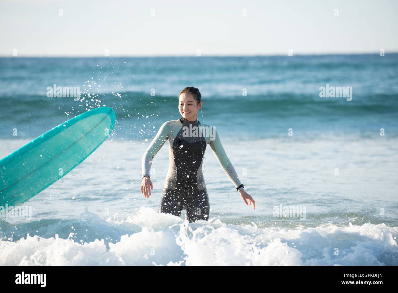 Frau im Neoprenanzug mit Surfbrett Stockfoto