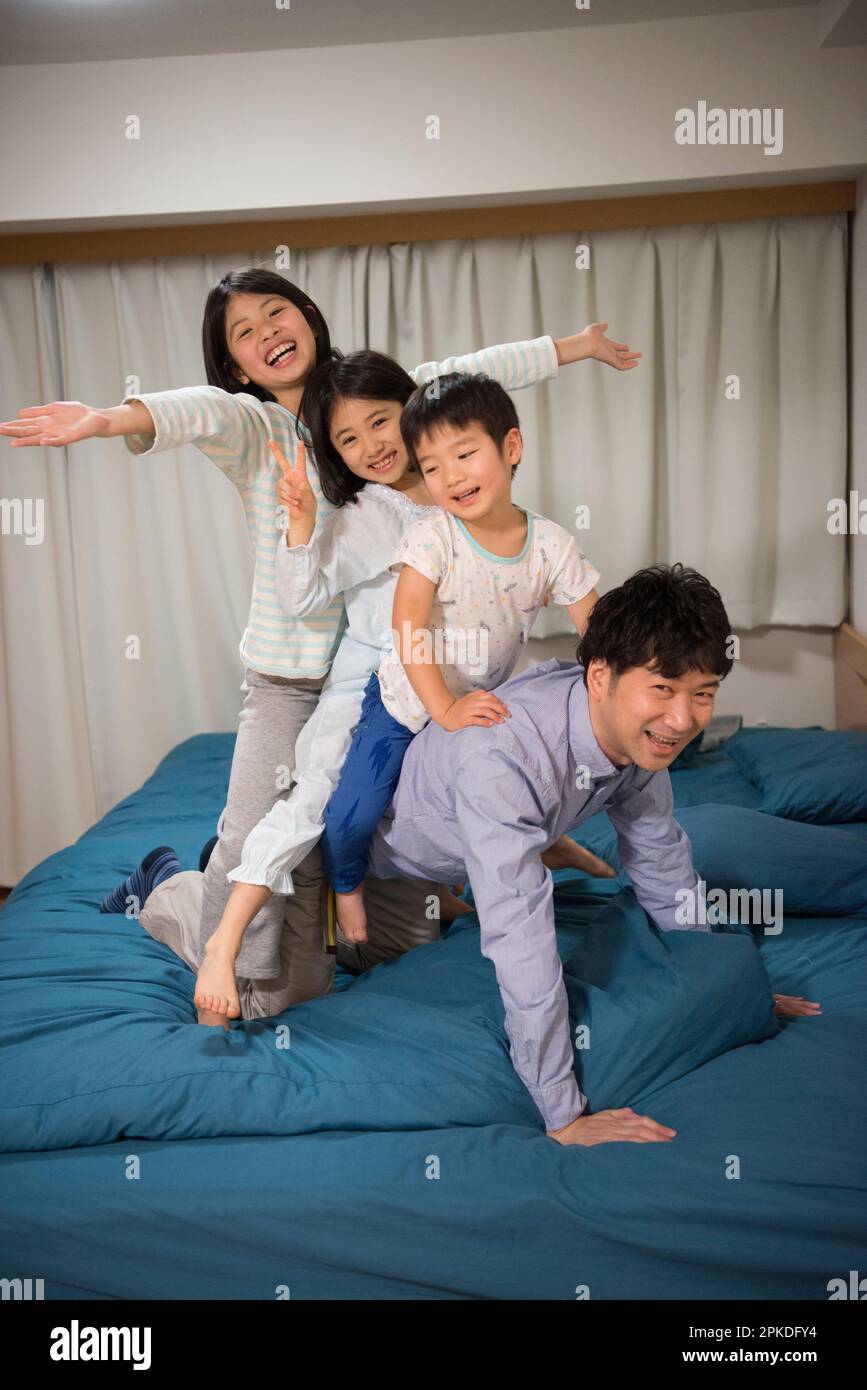 Vater mit Kindern, die auf dem Bett spielen Stockfoto