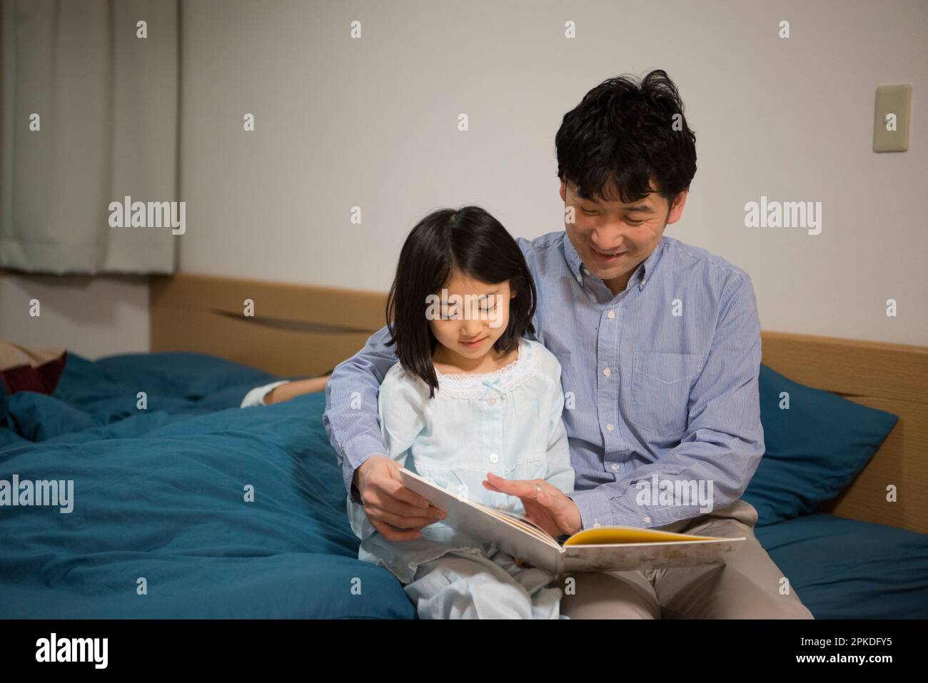 Kind und Vater beim Lesen von Bilderbüchern im Pyjama Stockfoto