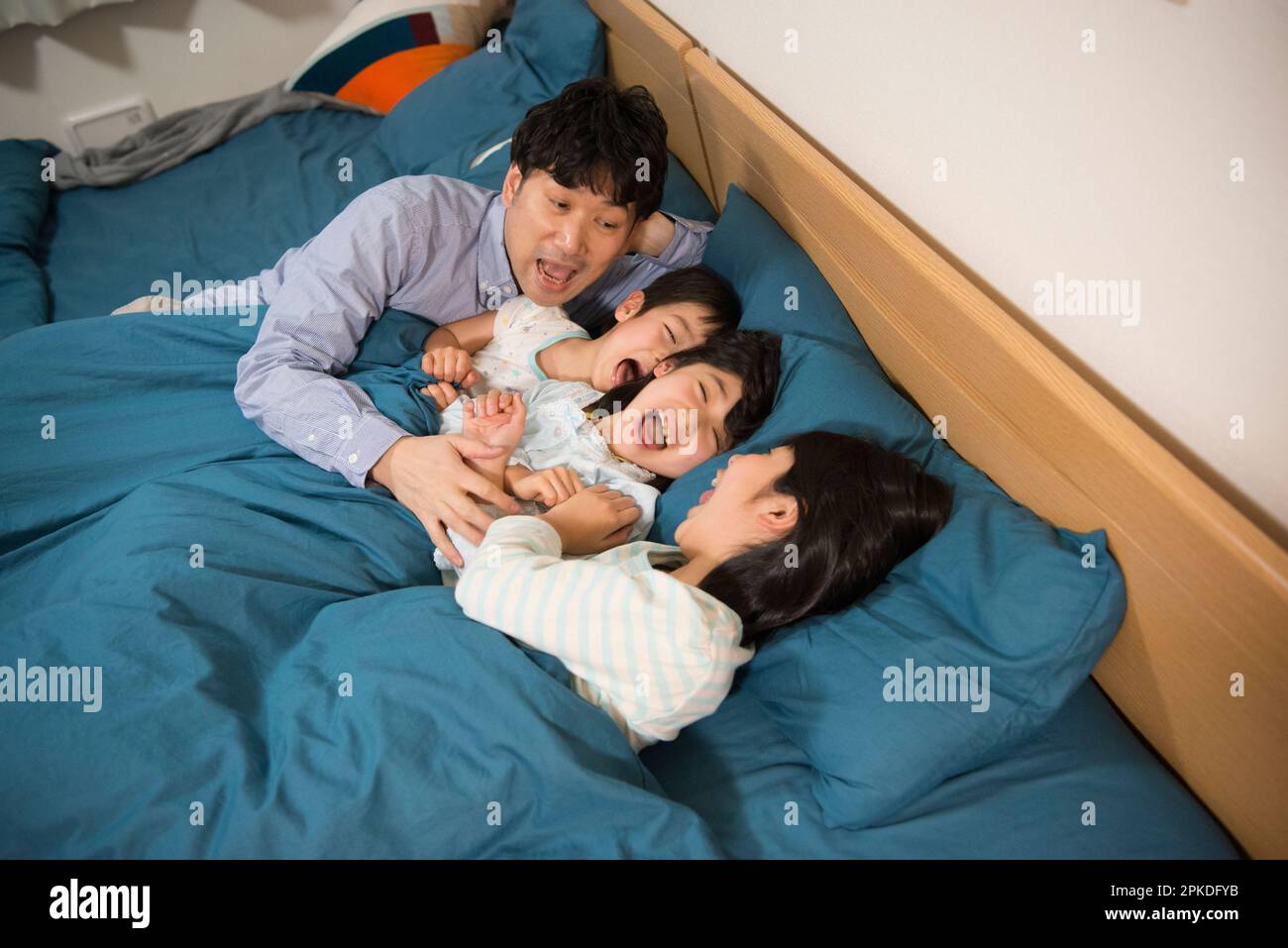 Vater mit Kindern, die auf dem Bett spielen Stockfoto