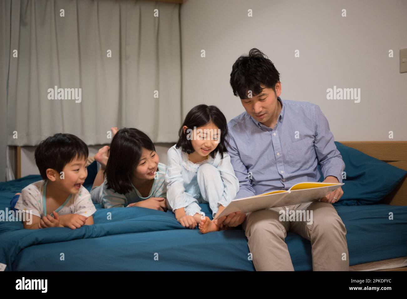 Kind und Vater beim Lesen von Bilderbüchern im Pyjama Stockfoto