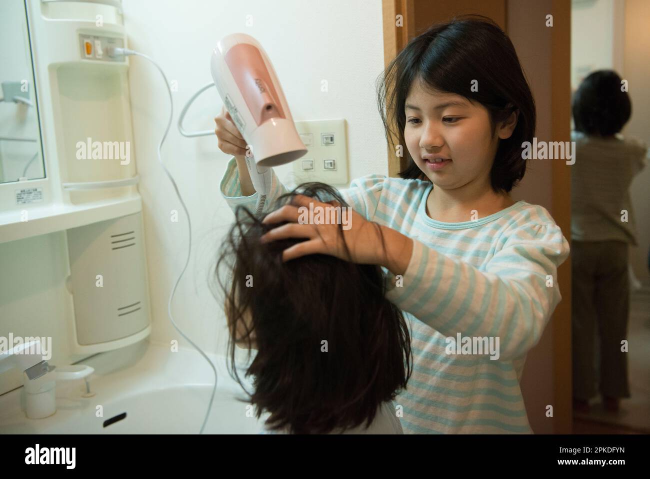 Schwestern trocknen ihre Haare mit einem Fön Stockfoto