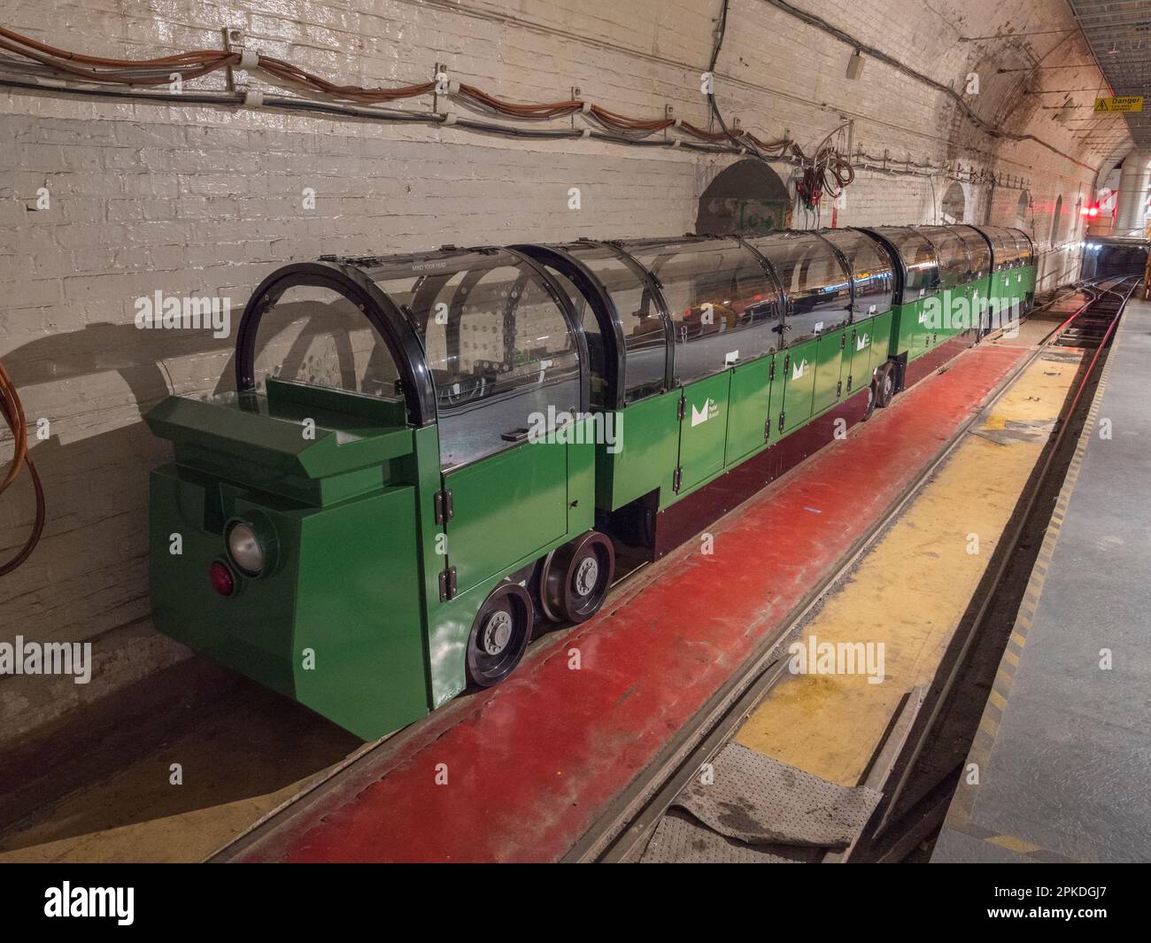 Einer der angepassten Touristenzüge von Mail Rail, dem ehemaligen Postamt-Eisenbahnsystem unter den Straßen von Central London, Vereinigtes Königreich. Stockfoto