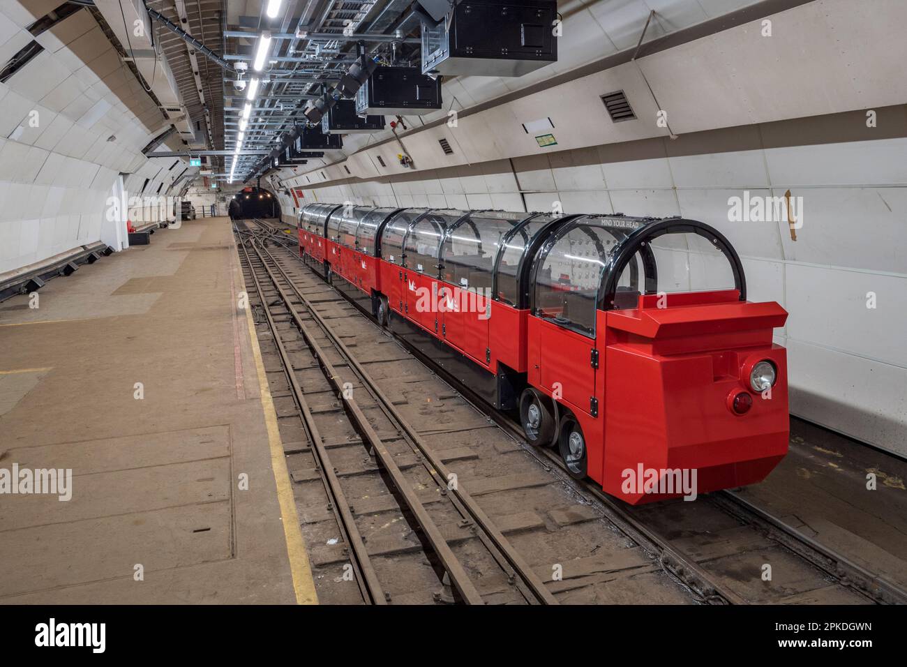 Einer der angepassten Touristenzüge von Mail Rail, dem ehemaligen Postamt-Eisenbahnsystem unter den Straßen von Central London, Vereinigtes Königreich. Stockfoto