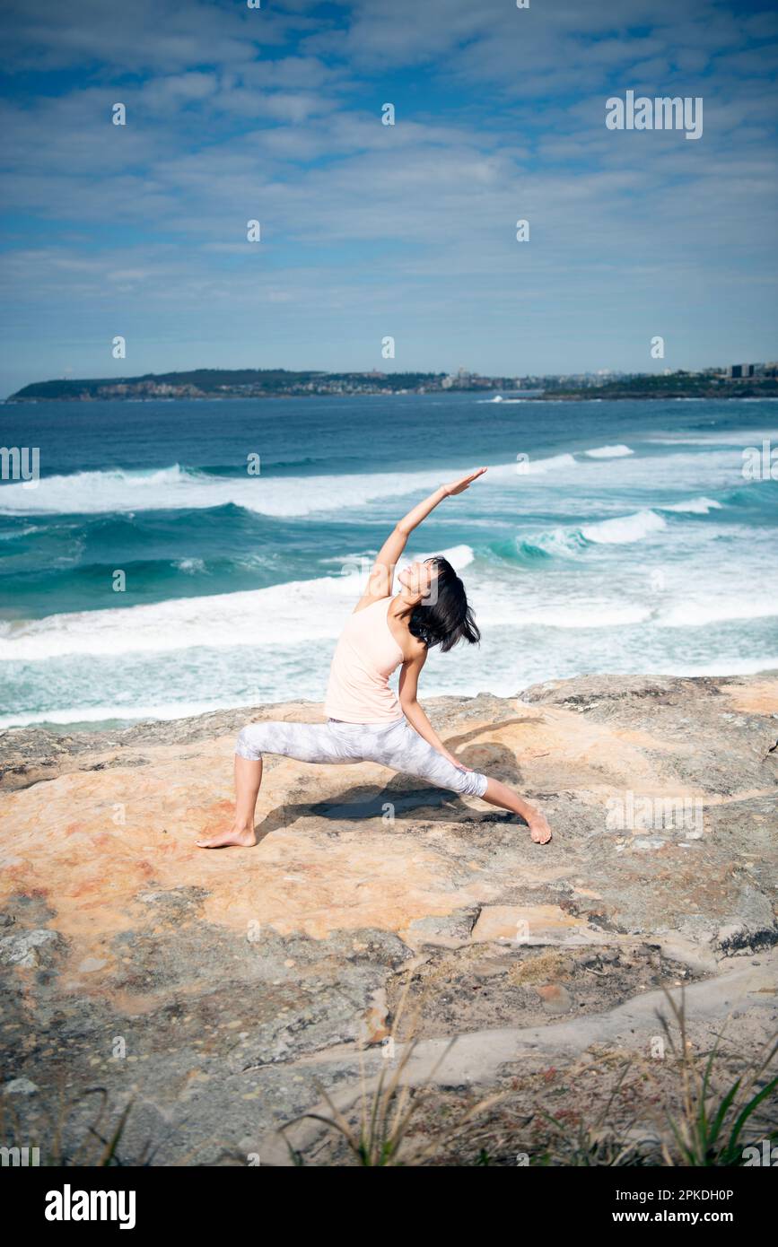 Eine Frau, die Yoga im Meer macht Stockfoto