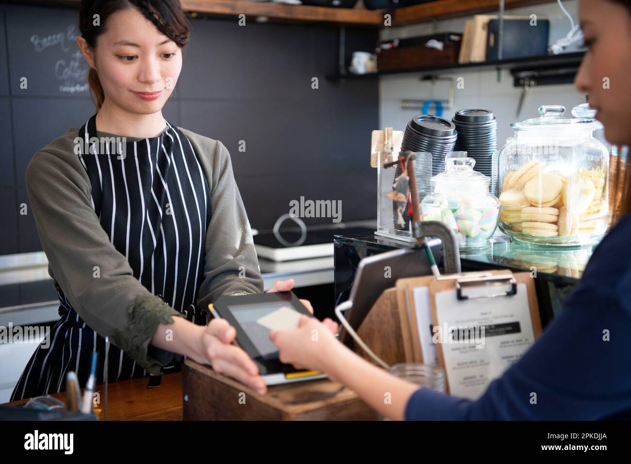 Eine Frau, die elektronische Zahlungen in einem Laden tätigt Stockfoto