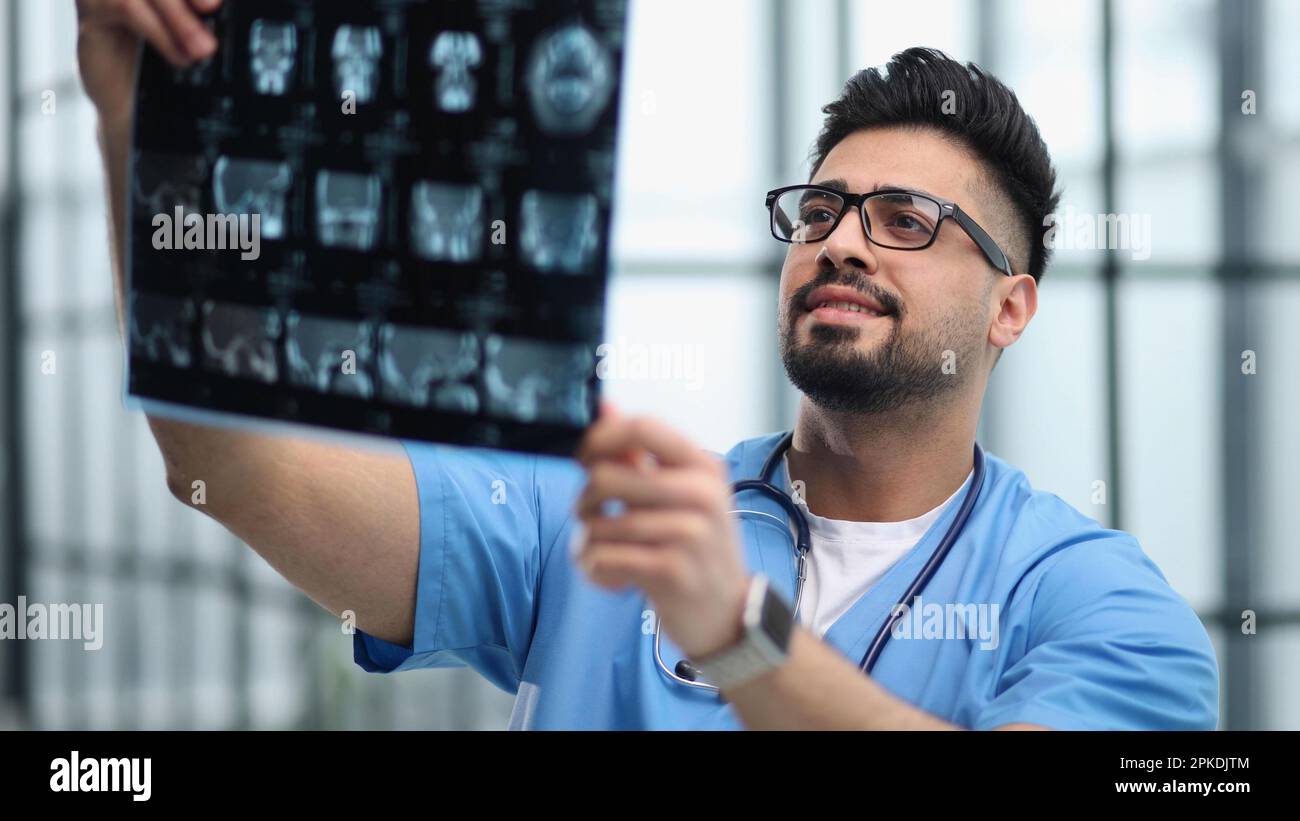 Ein weißer Arzt in Uniform sieht sich das Röntgenbild an Stockfoto