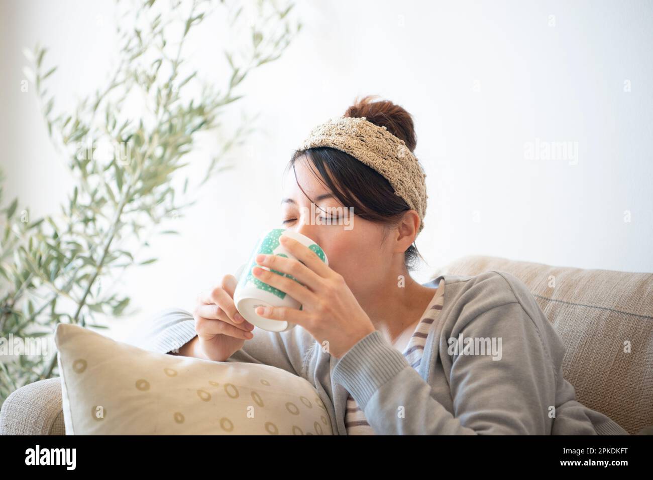 Eine Frau, die sich auf dem Sofa entspannt, während sie Tee trinkt Stockfoto