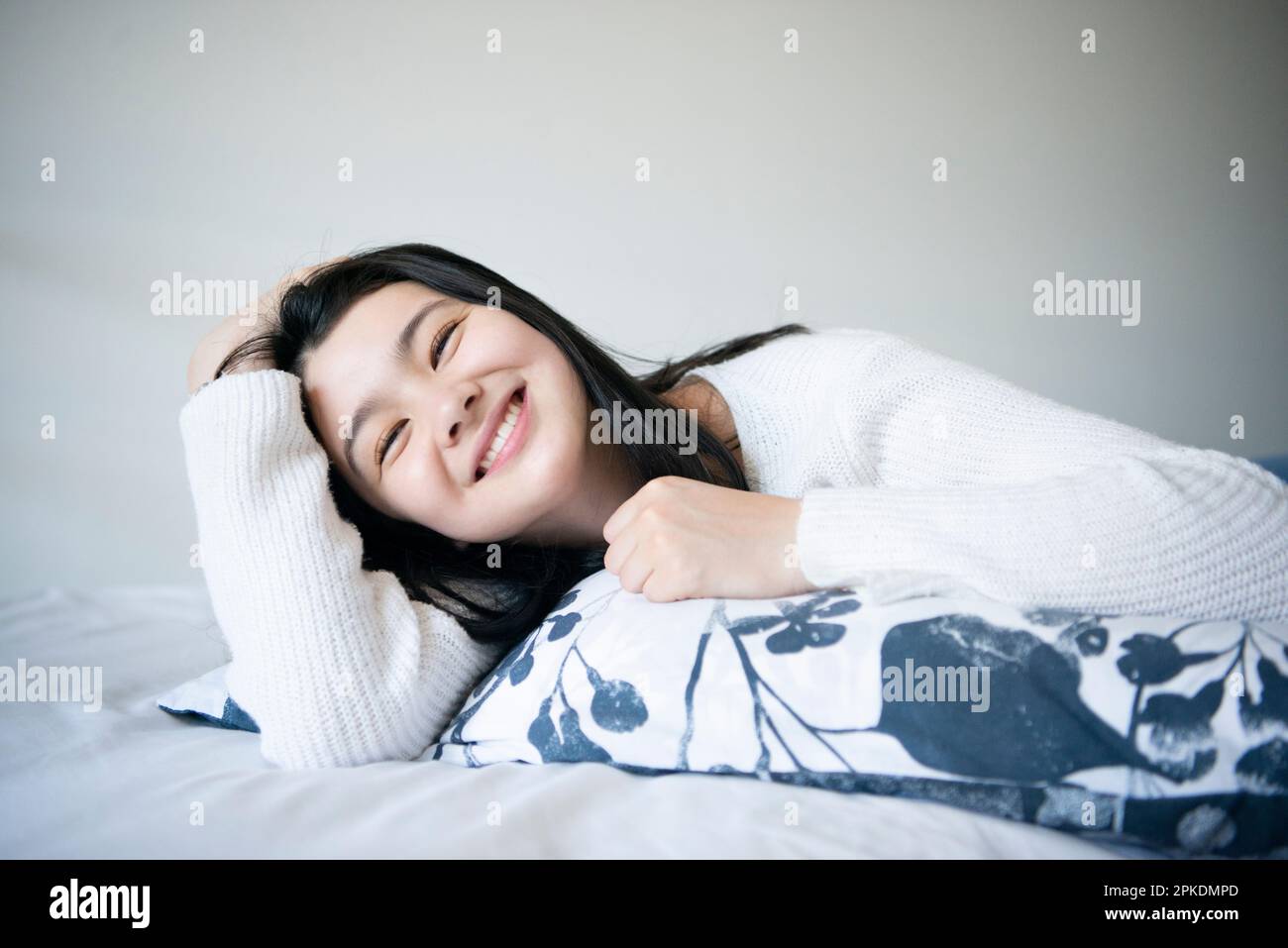 Eine Frau, die im Bett liegt und lacht Stockfoto