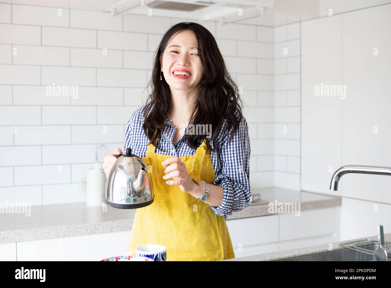 Eine Frau, die eine Schürze trägt und in der Küche lacht Stockfoto