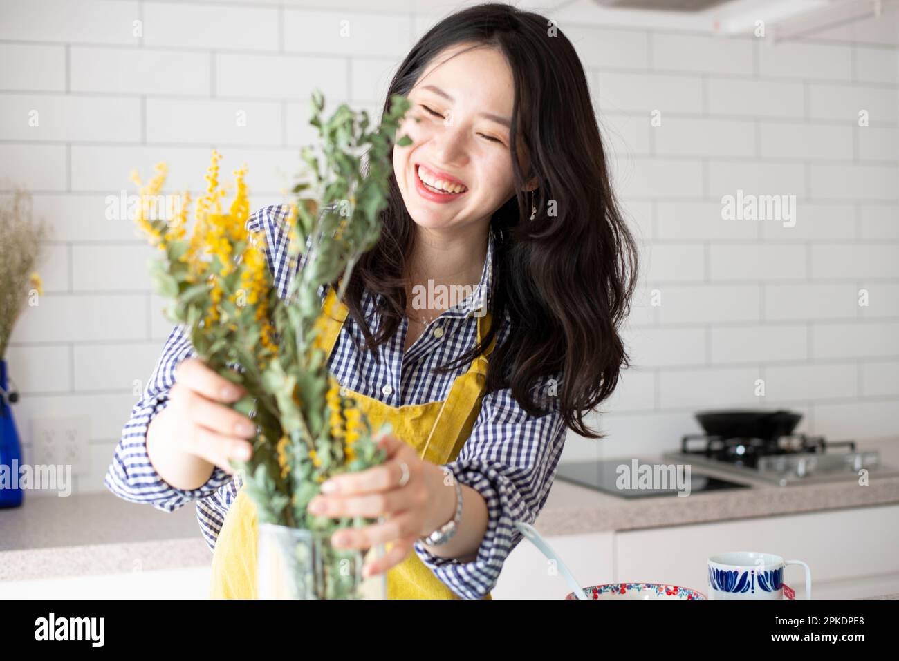 Frau mit Schürze und Blumen in der Küche Stockfoto